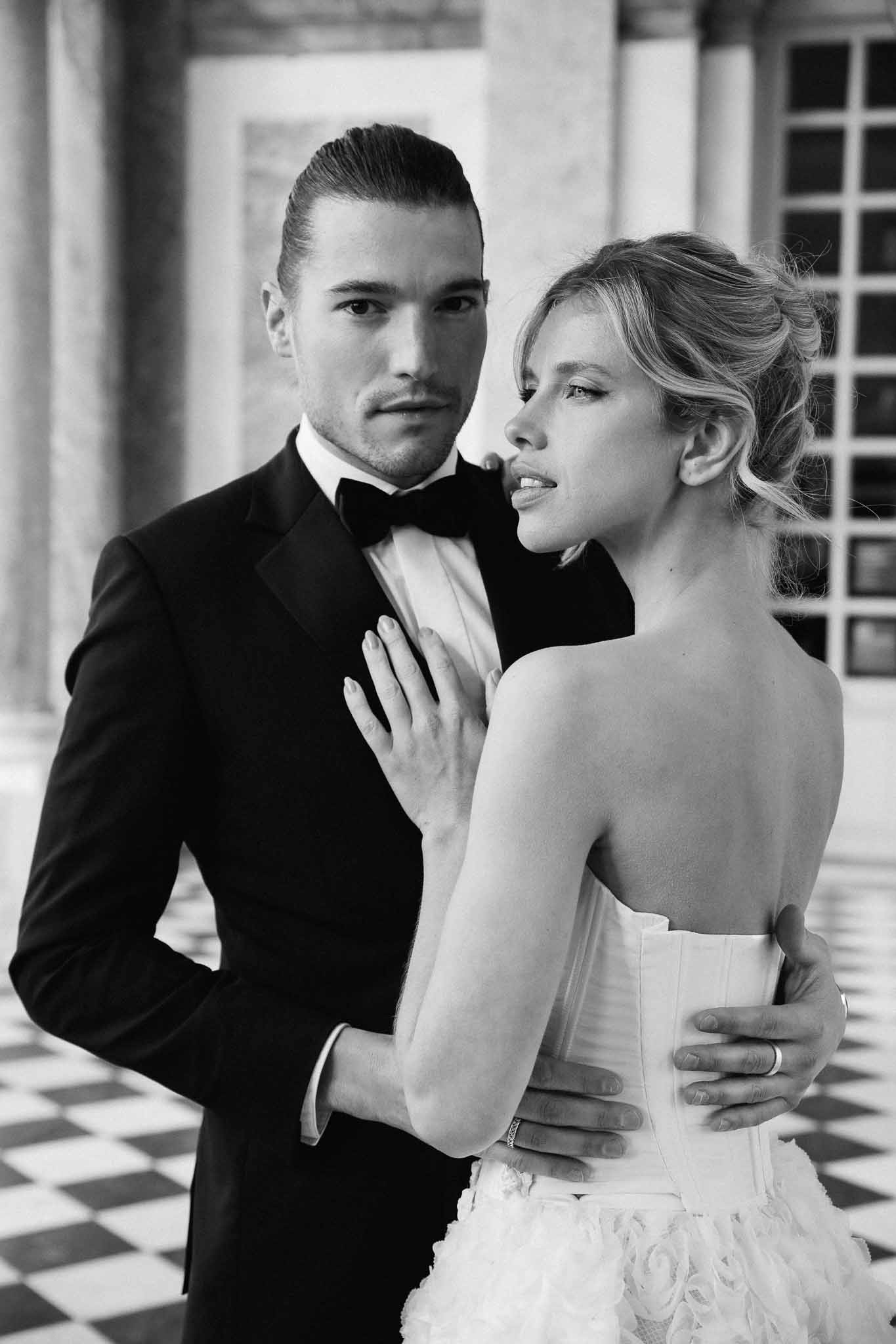 Black and white portrait of bride and groom posing together in classical columned indoor venue