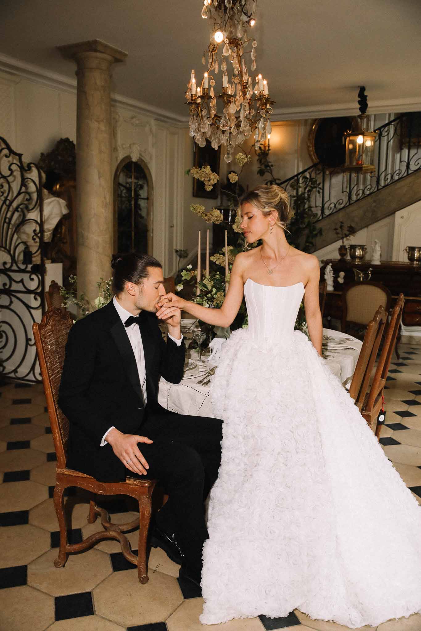 Bride and groom sharing intimate moment during reception in grand classical dining room with crystal chandelier