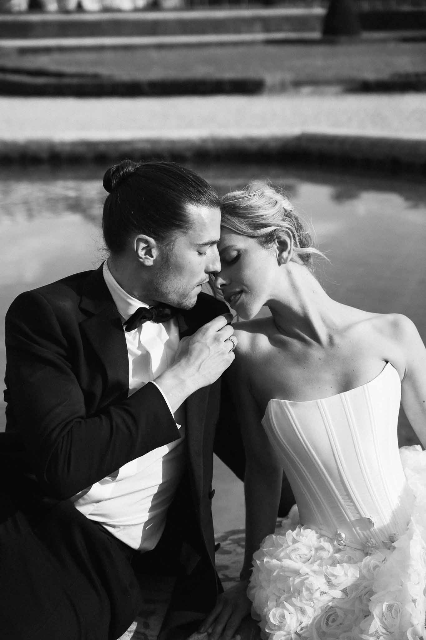 Black and white portrait of bride and groom in intimate pose at outdoor waterside wedding venue