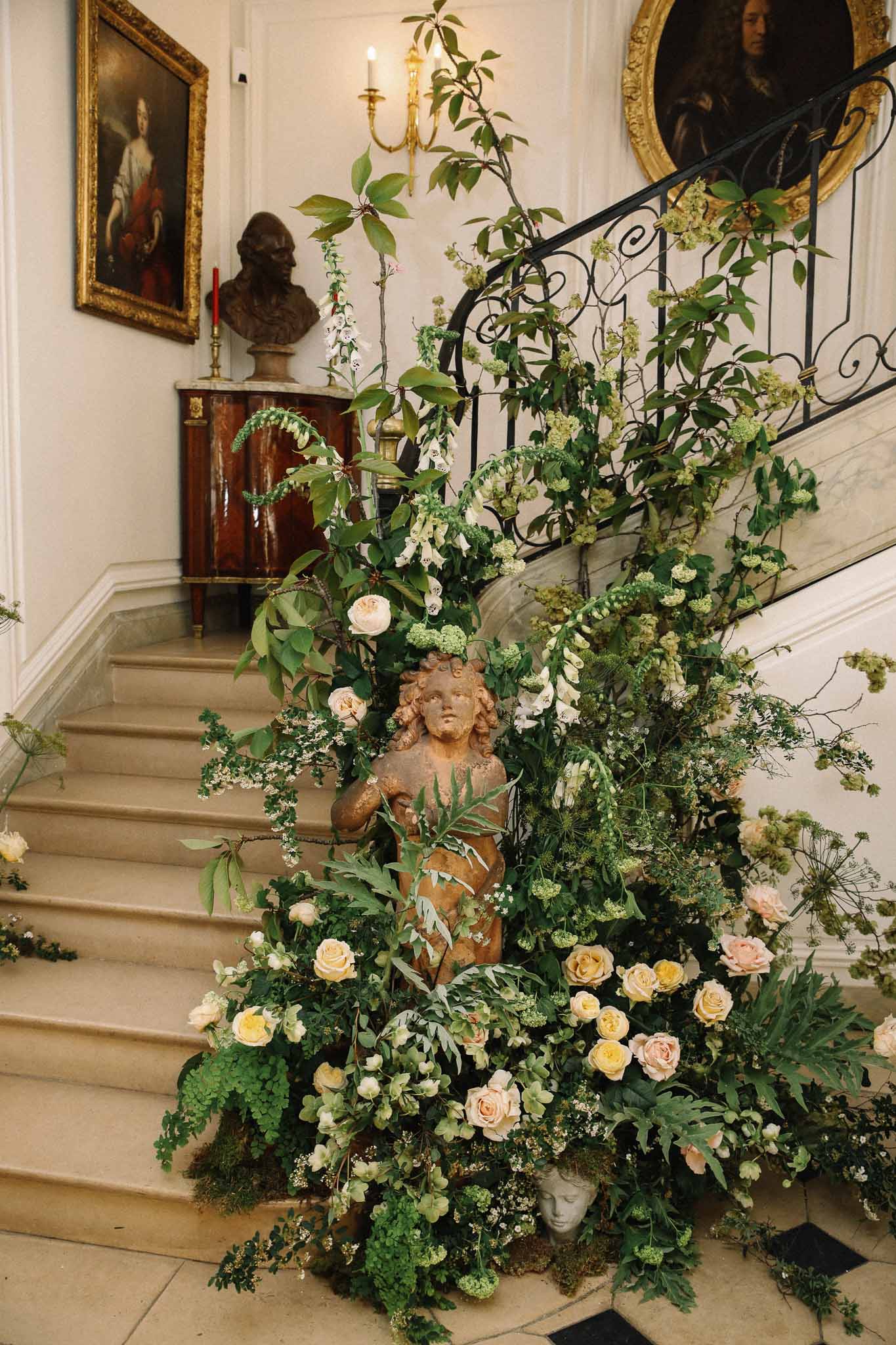 Elaborate floral staircase installation with peach roses and greenery in classical interior venue