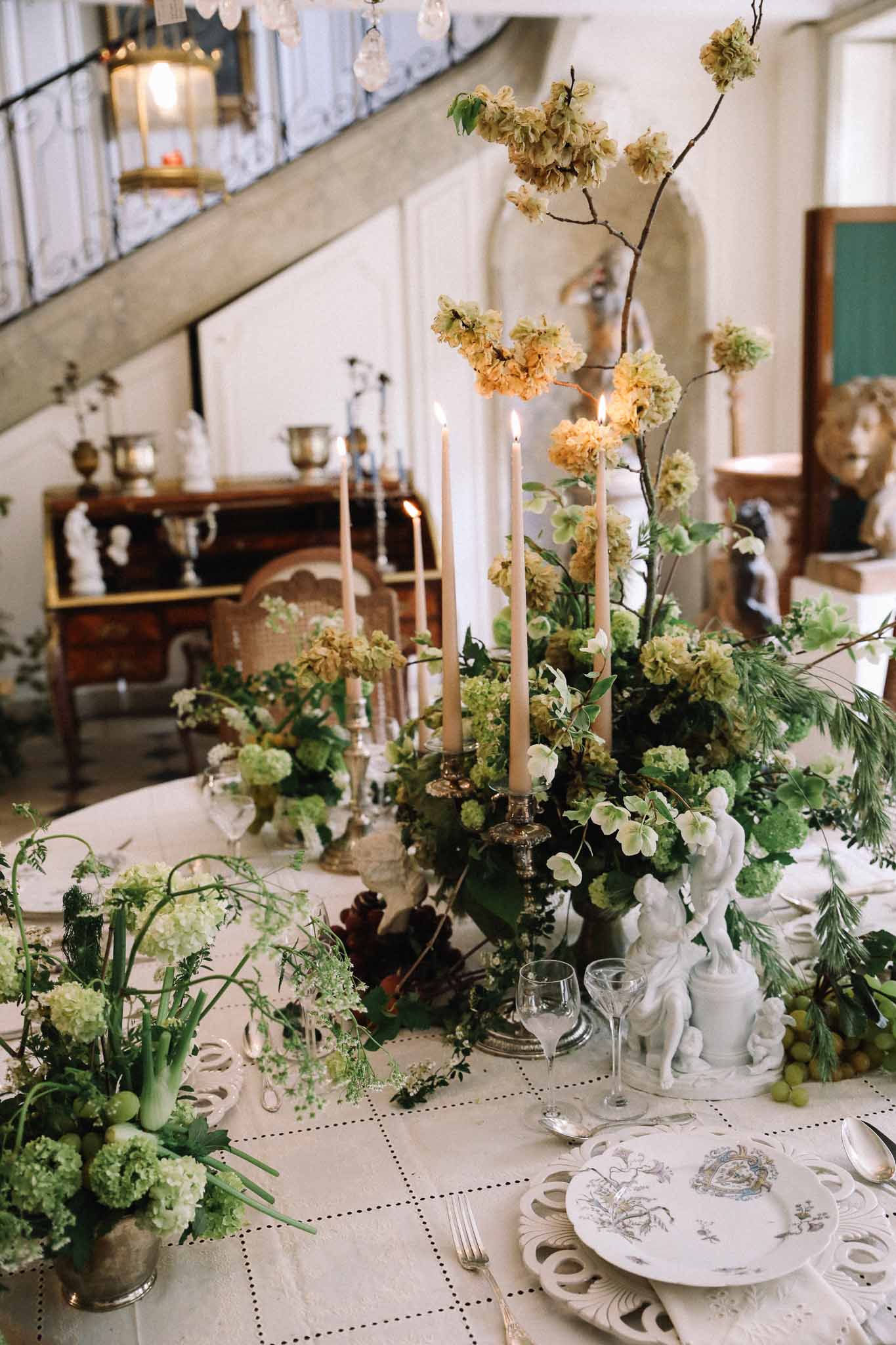Elegant reception tablescape with brass candelabras and mixed greenery centerpiece at indoor wedding venue