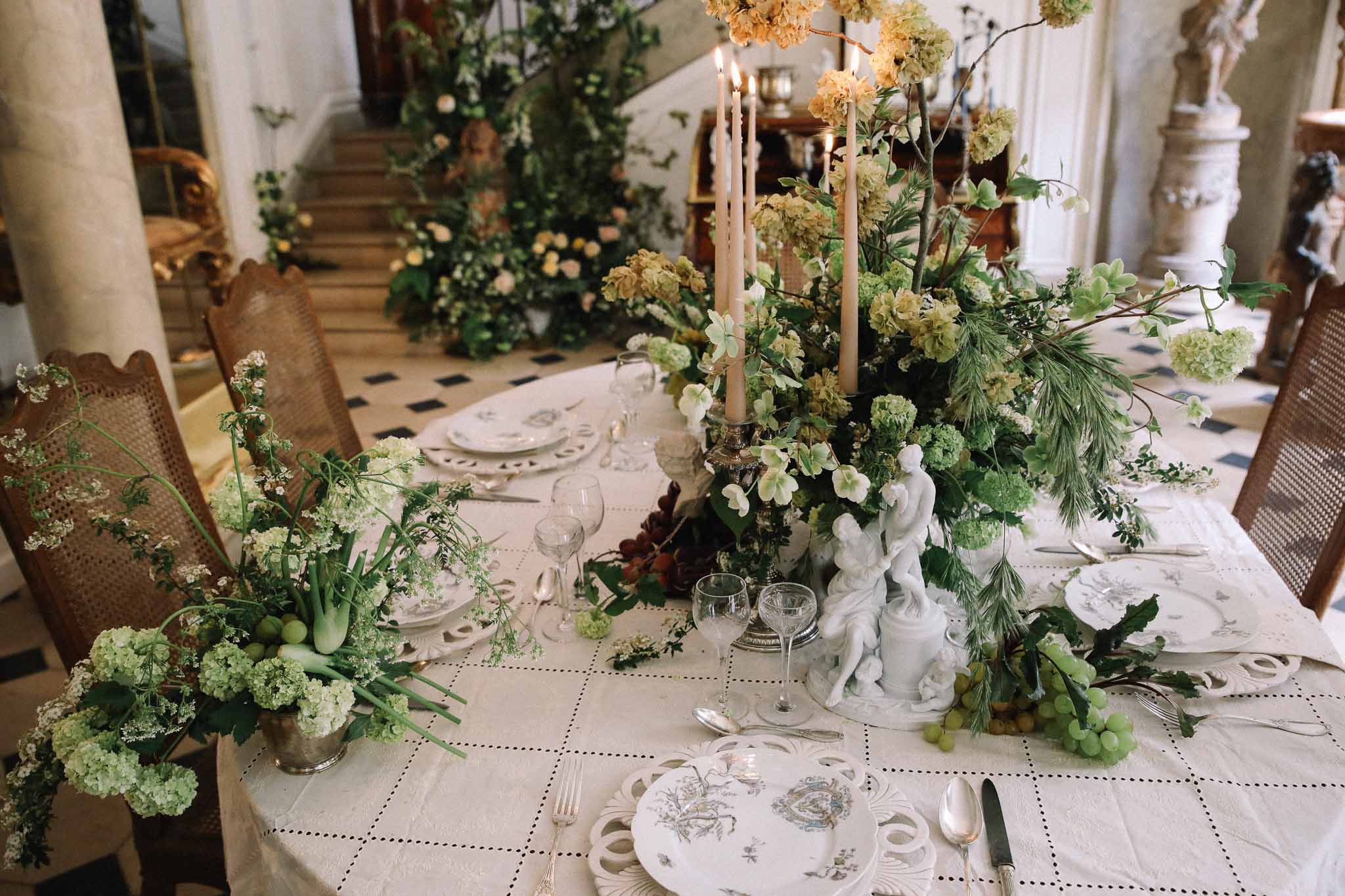 Reception dinner table with floral centerpieces and place settings in classical indoor venue