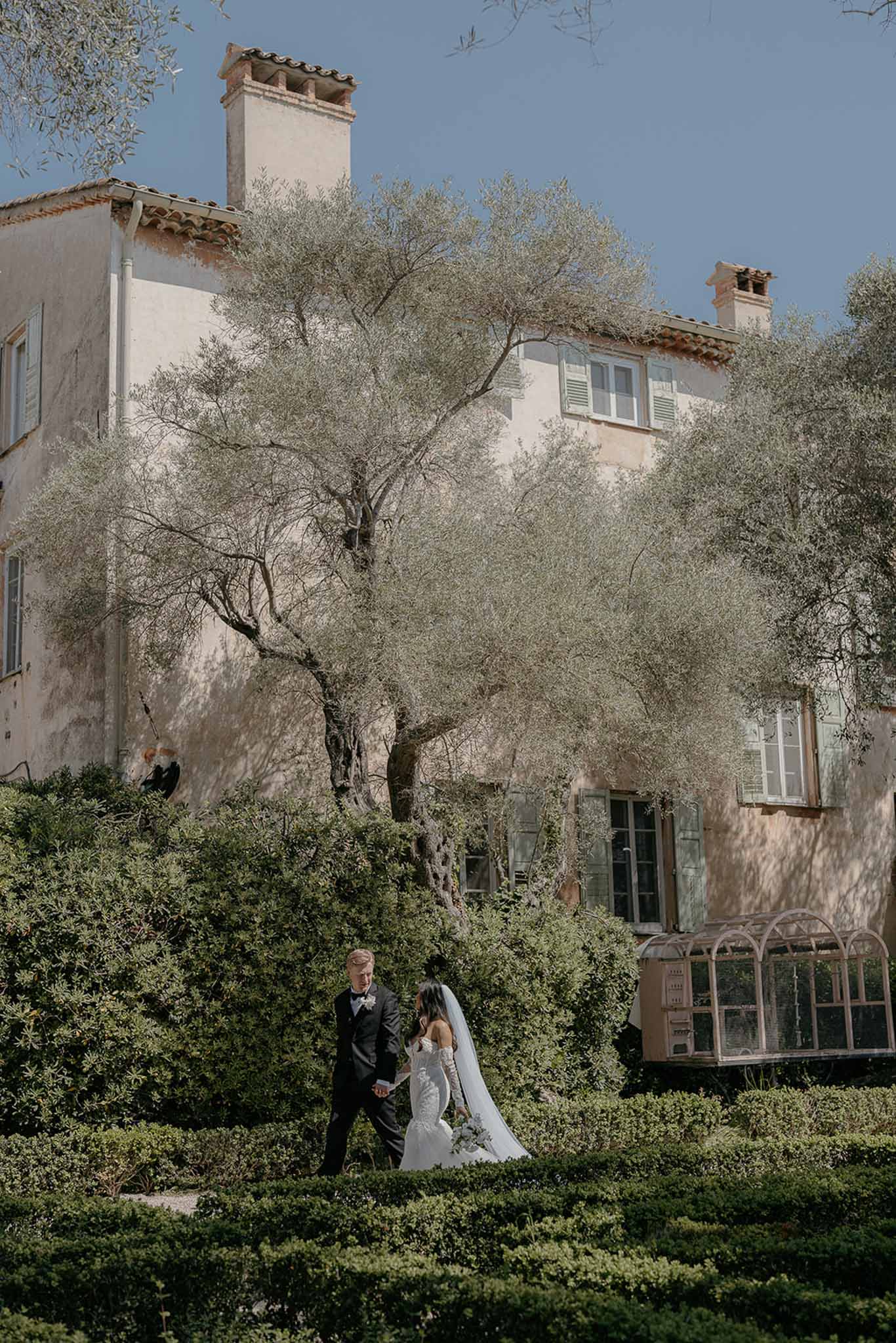 Bride and groom walking hand in hand in a garden