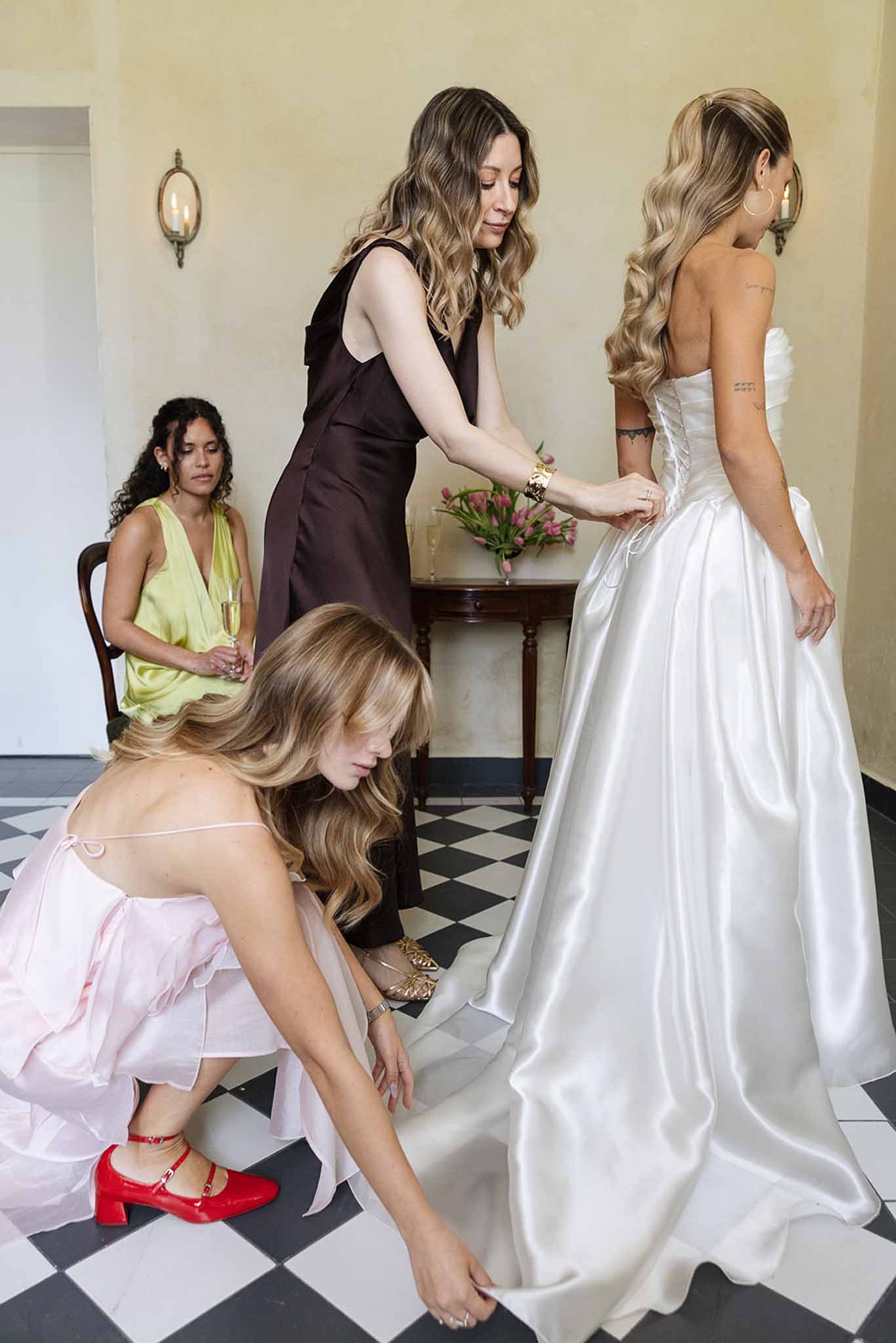 Bride being prepared by bridal party members in elegant indoor getting ready space