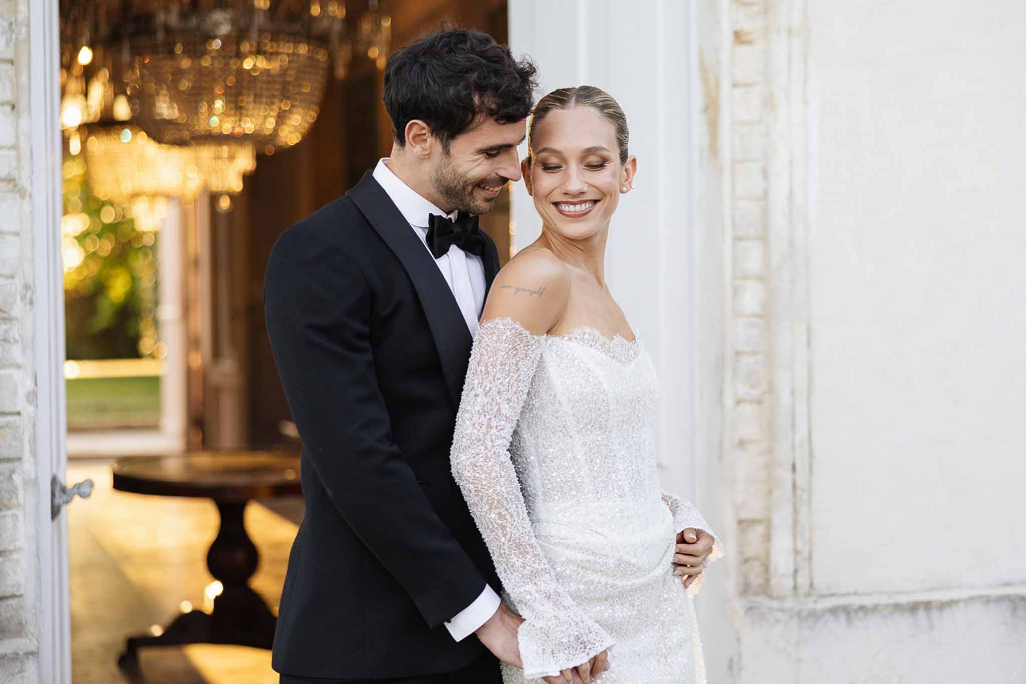 Bride and groom formal portrait at elegant venue entrance with golden lighting