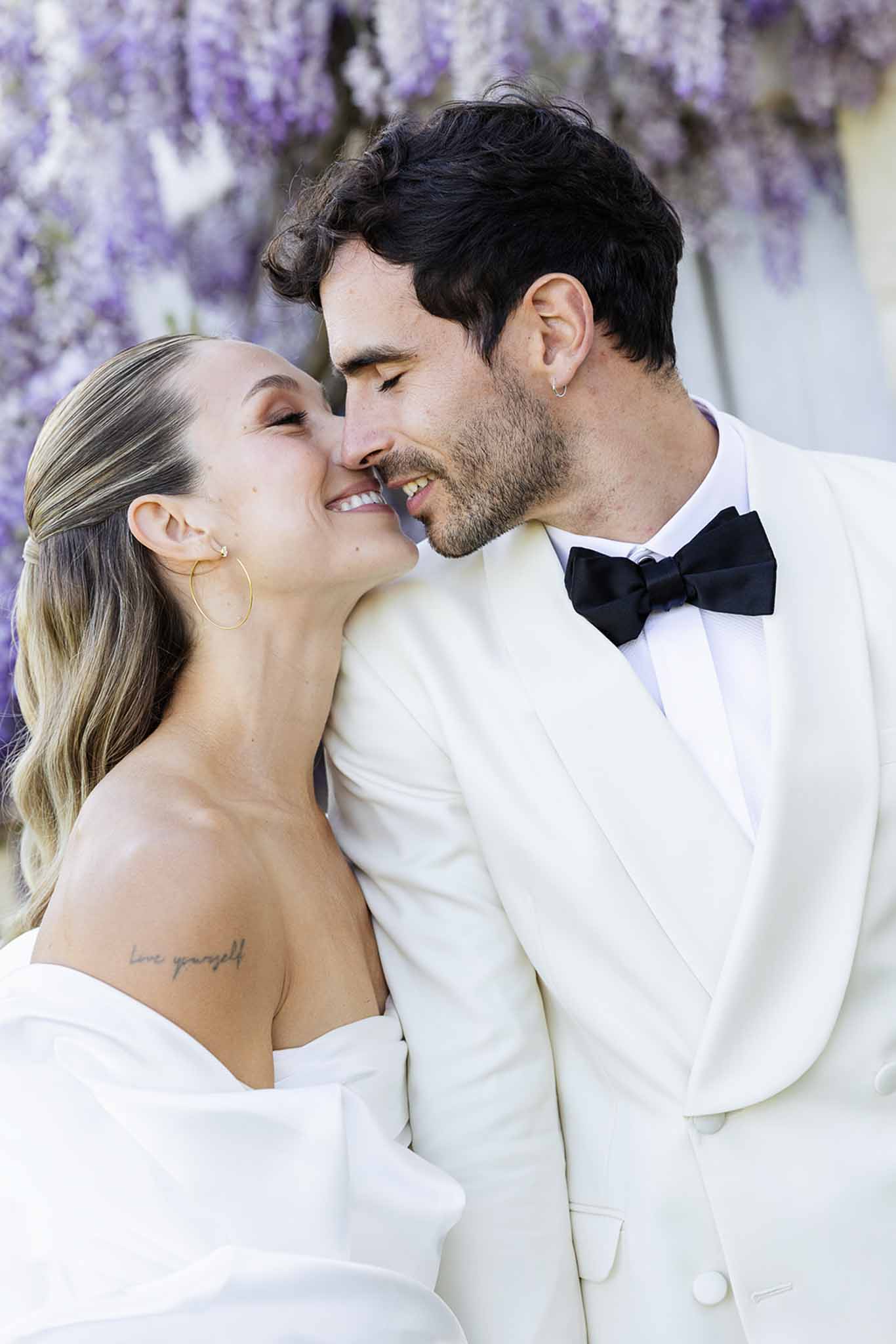 Bride and groom intimate portrait with wisteria flowers backdrop at outdoor wedding venue