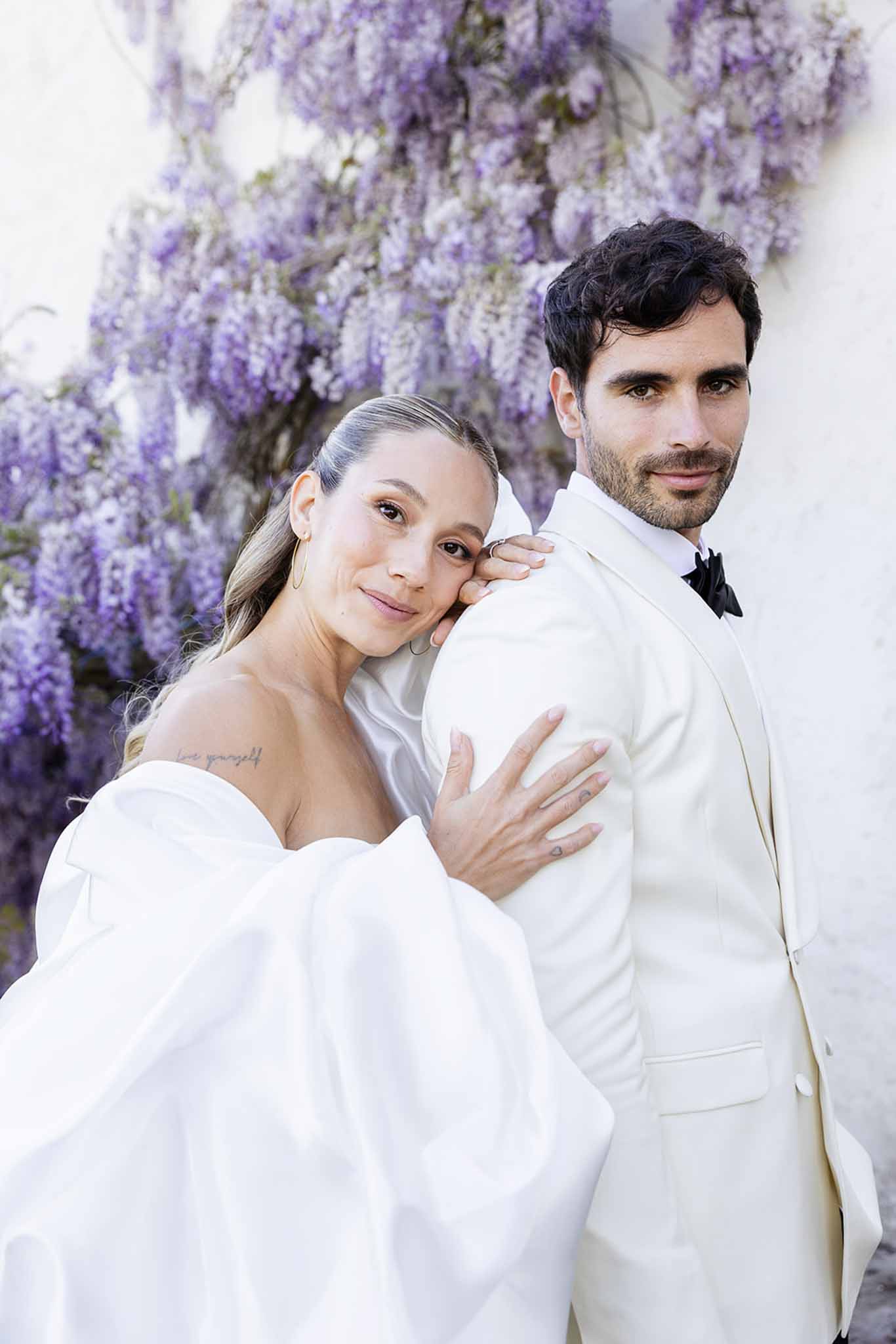 Bride and groom portrait with wisteria backdrop at garden wedding venue