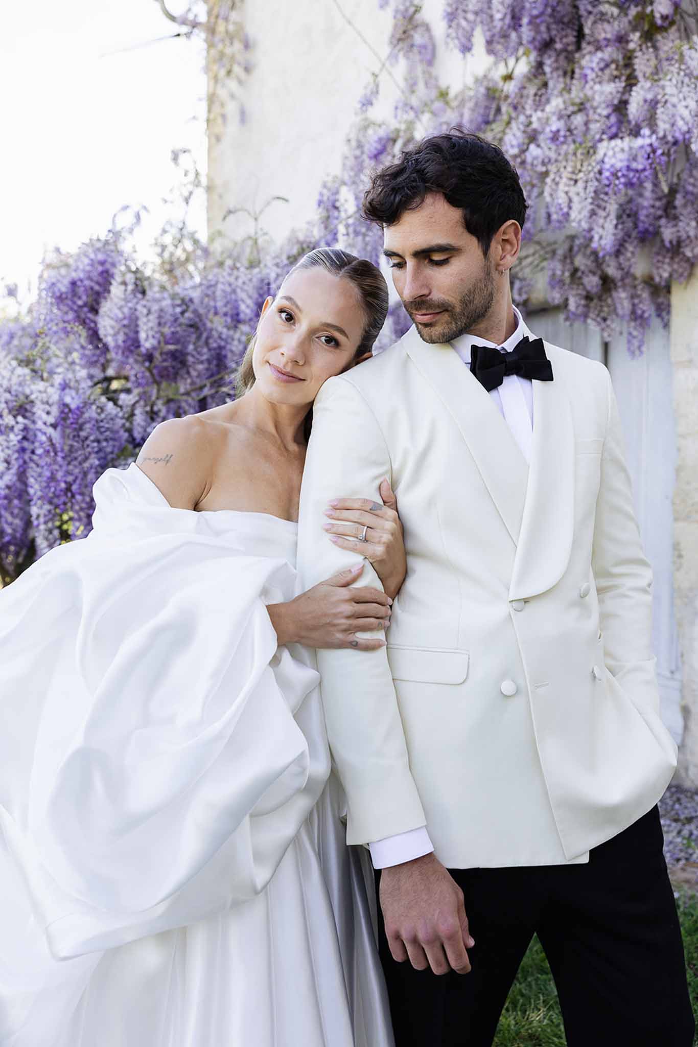 Bride and groom portrait with purple wisteria floral backdrop at wedding venue