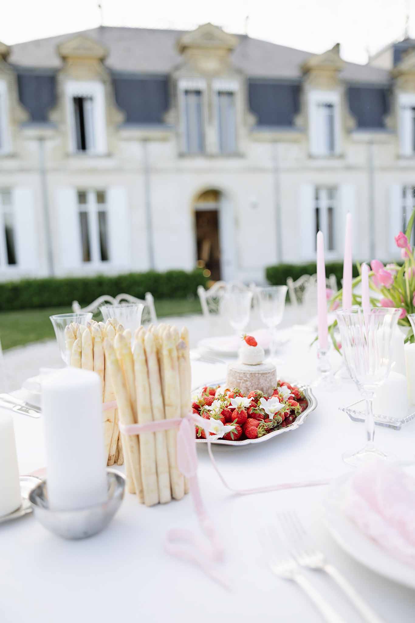 White reception table setting with pink ribbon details and strawberry centerpiece at French château garden venue