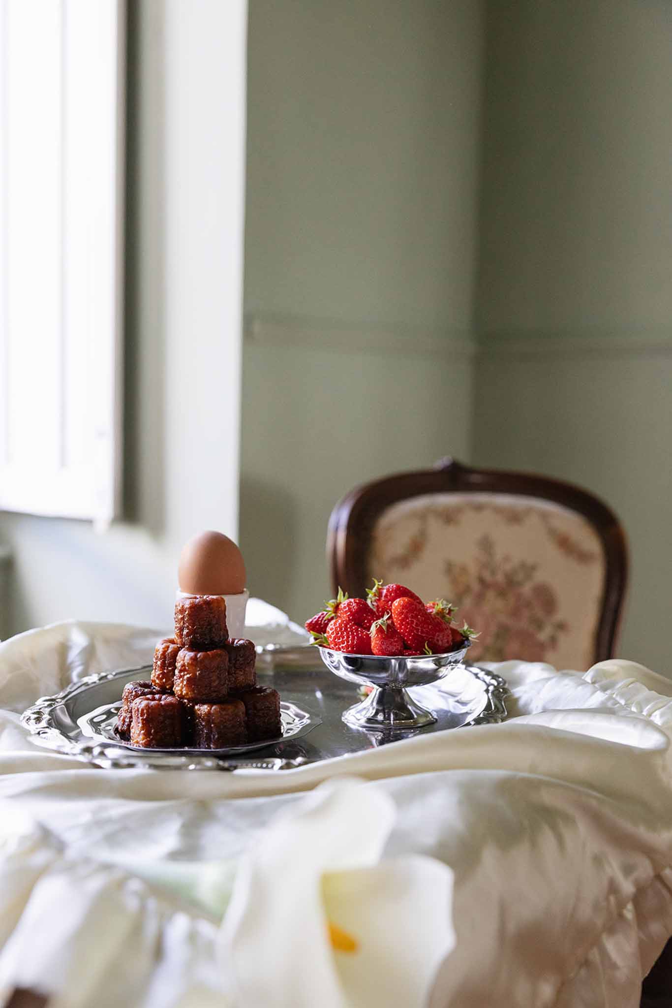 Chocolate cake and strawberry display on silver pedestals in bridal suite with cream linens