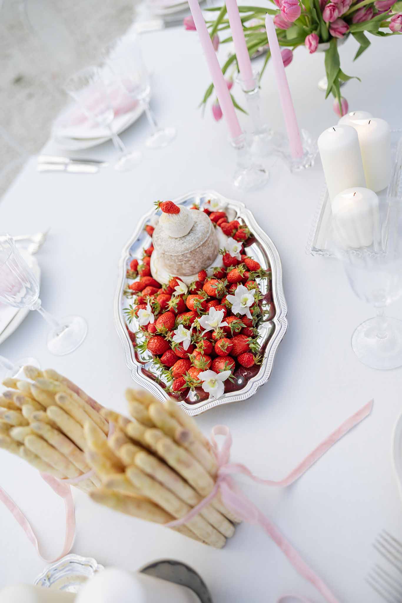 Elegant reception table setting with cream cake, strawberries, and pink floral arrangements at wedding venue