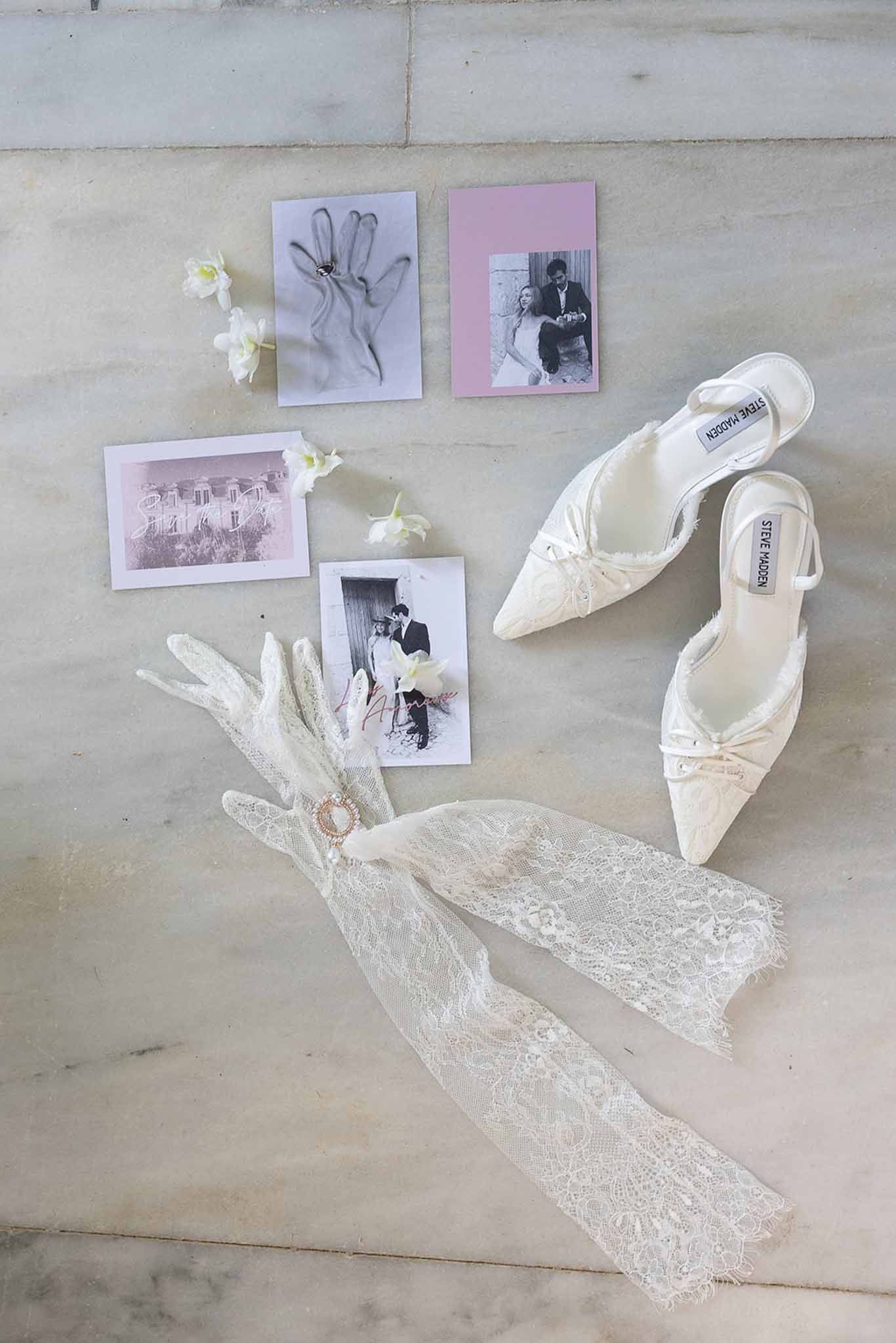 Bridal flat lay with ivory pointe shoes, lace veil, vintage photos and white ranunculus on concrete surface