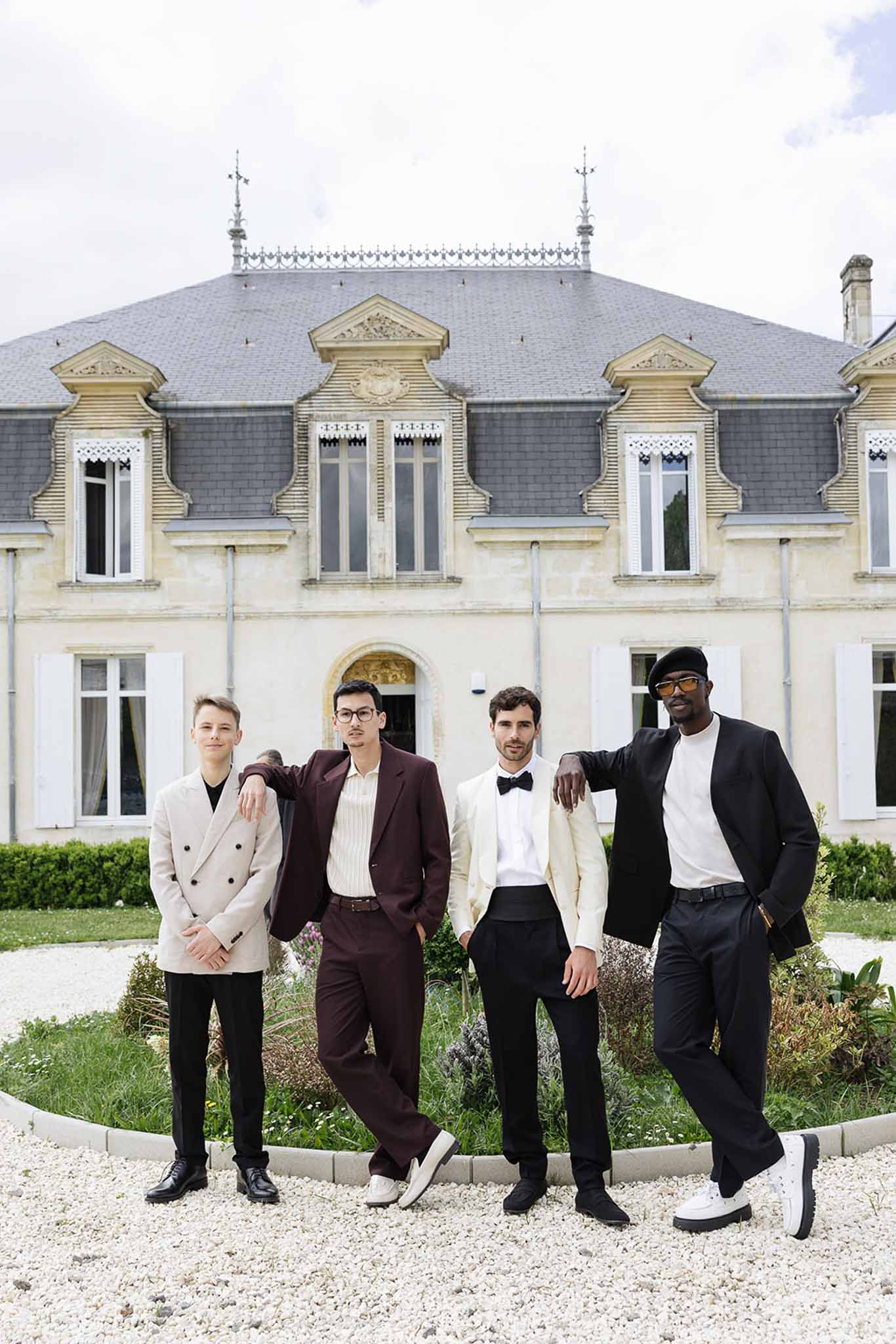 Four groomsmen in formal attire posing together at French château wedding venue