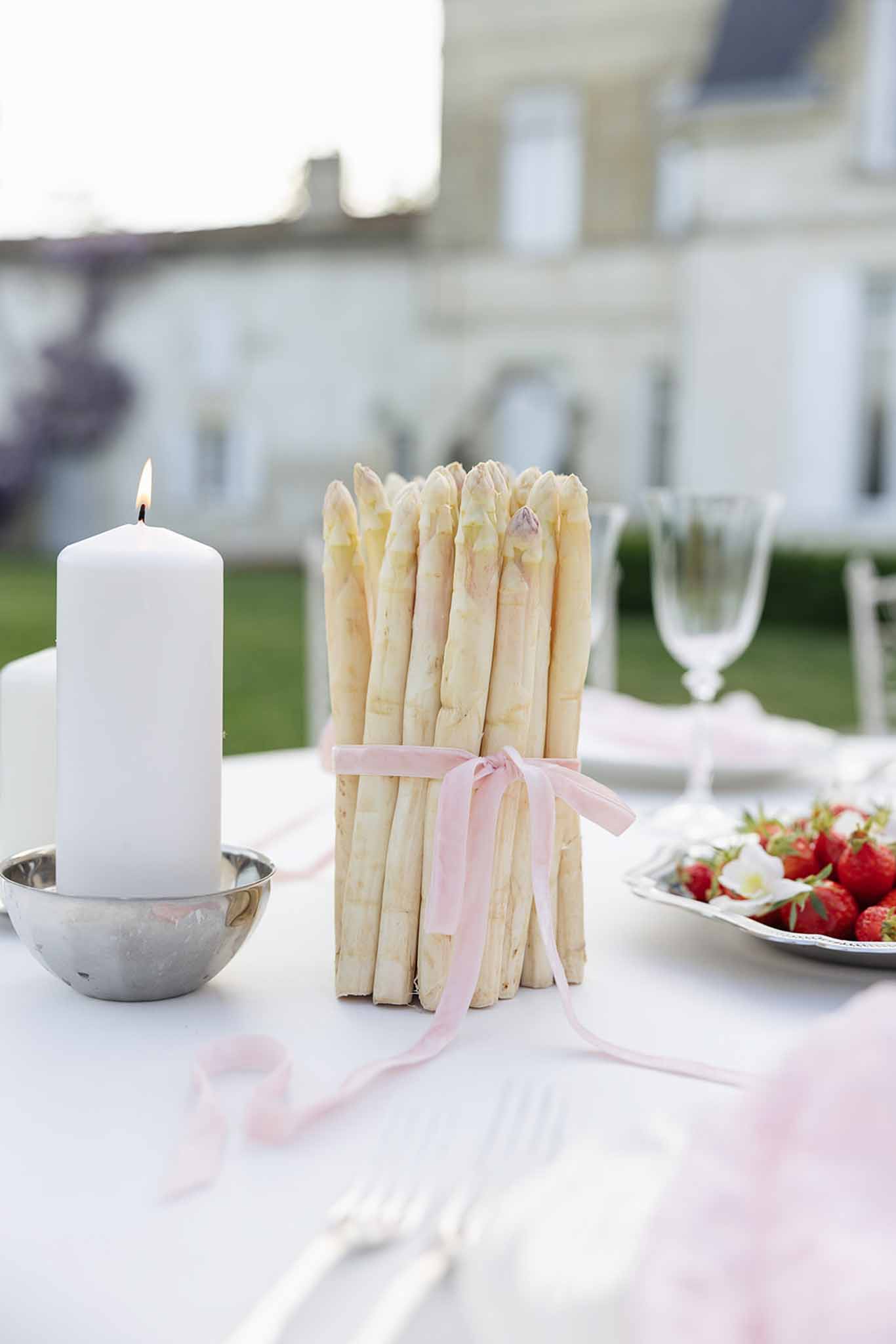 Reception table centerpiece with asparagus bundle and pink ribbon at outdoor wedding venue