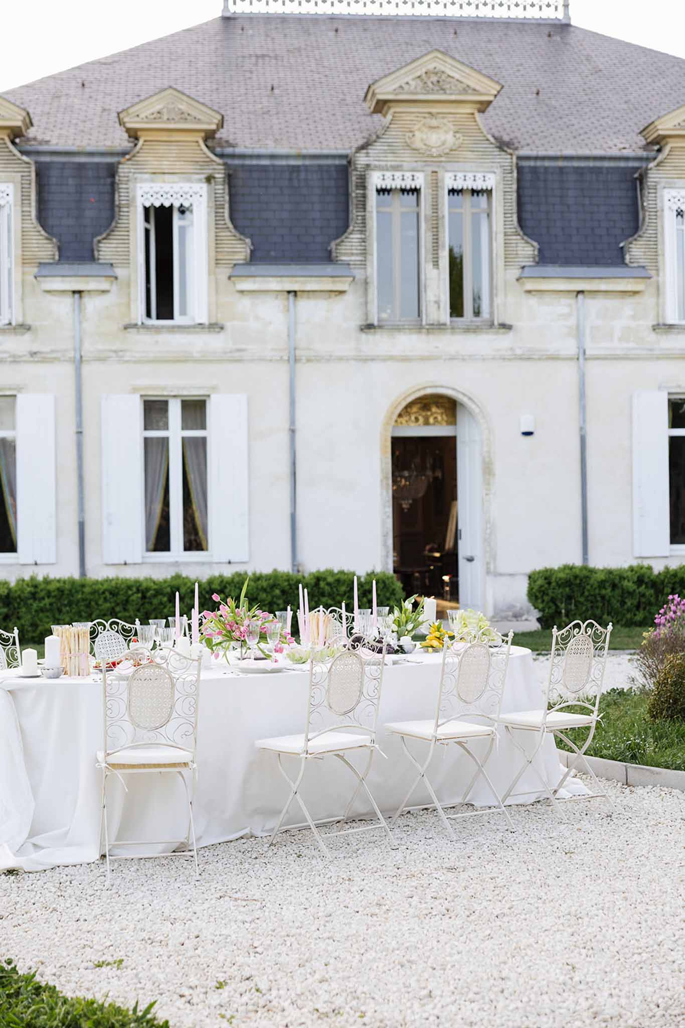 Outdoor reception setup in courtyard of French manor house with dining table and classical architecture