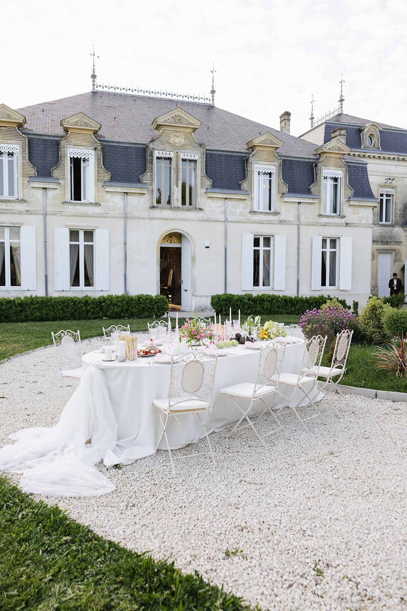Outdoor wedding reception with round tables on château courtyard gravel terrace
