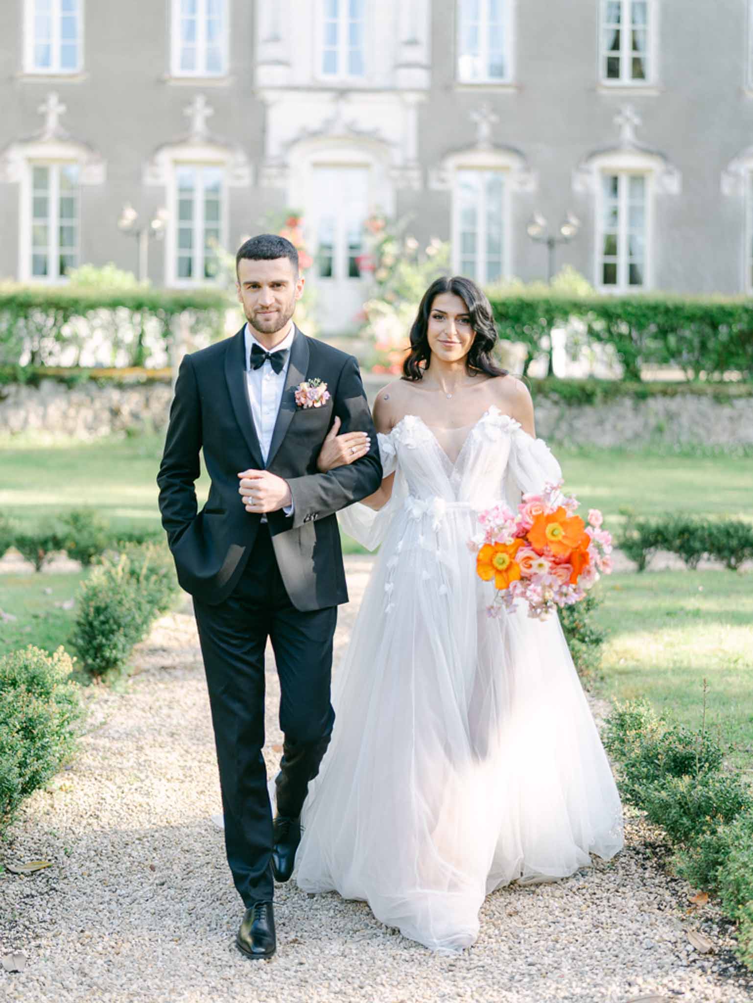 Bride and groom walking hand in hand in a garden