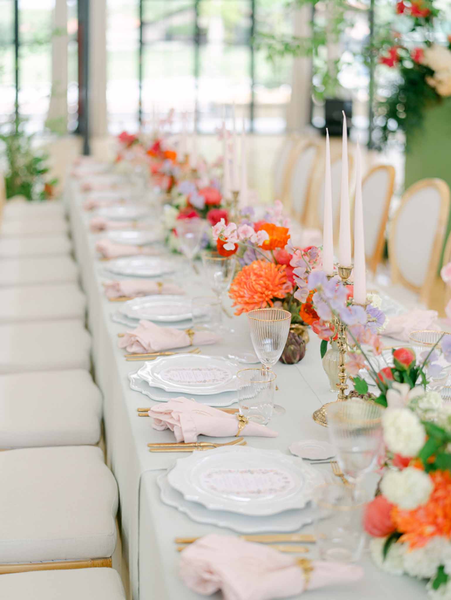 Reception table detail with orange dahlias, coral peonies, gold candelabras, and blush taper candles