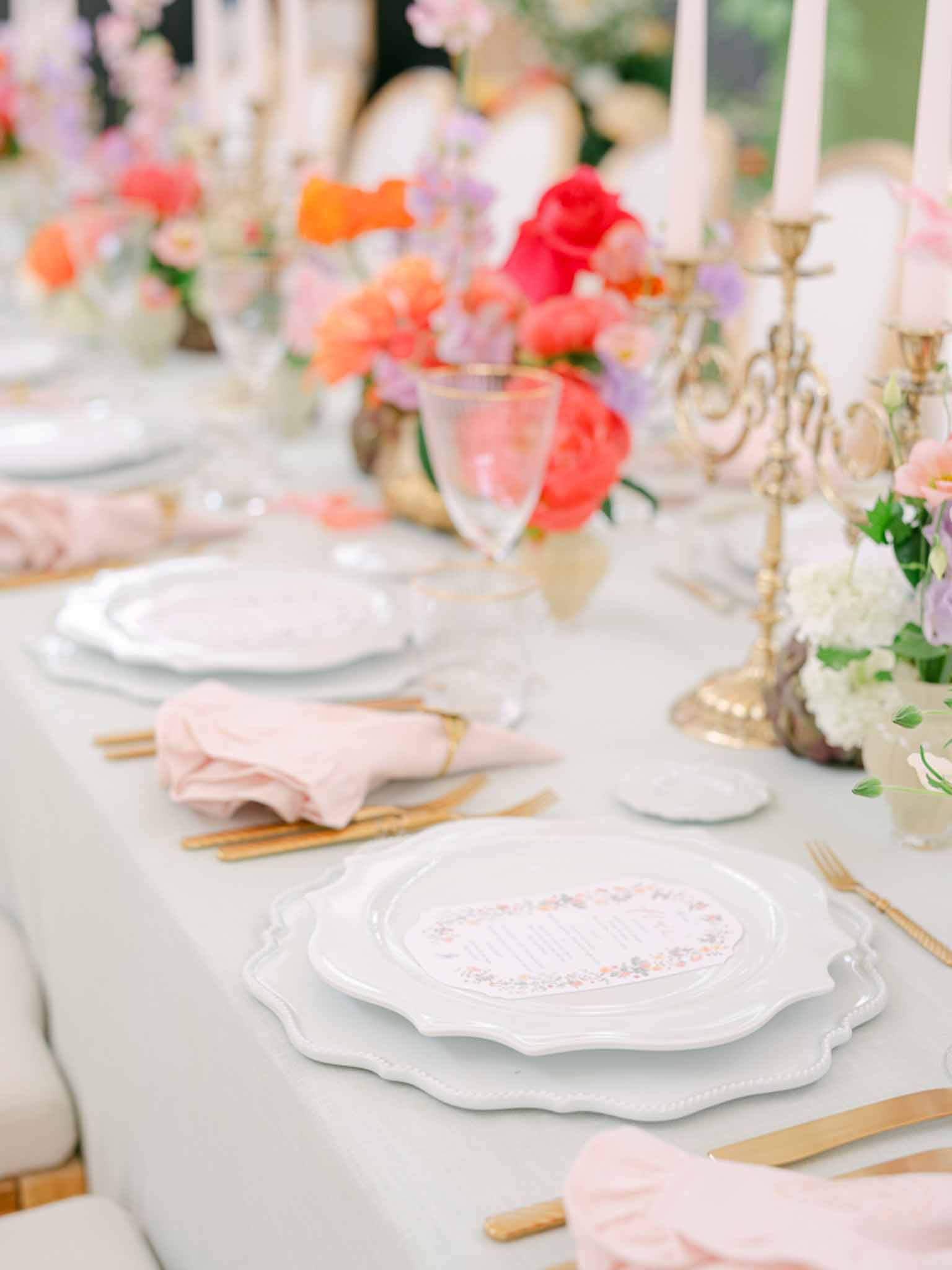 Reception table with coral peonies in gold vessels sage linen blush napkins and brass candelabras