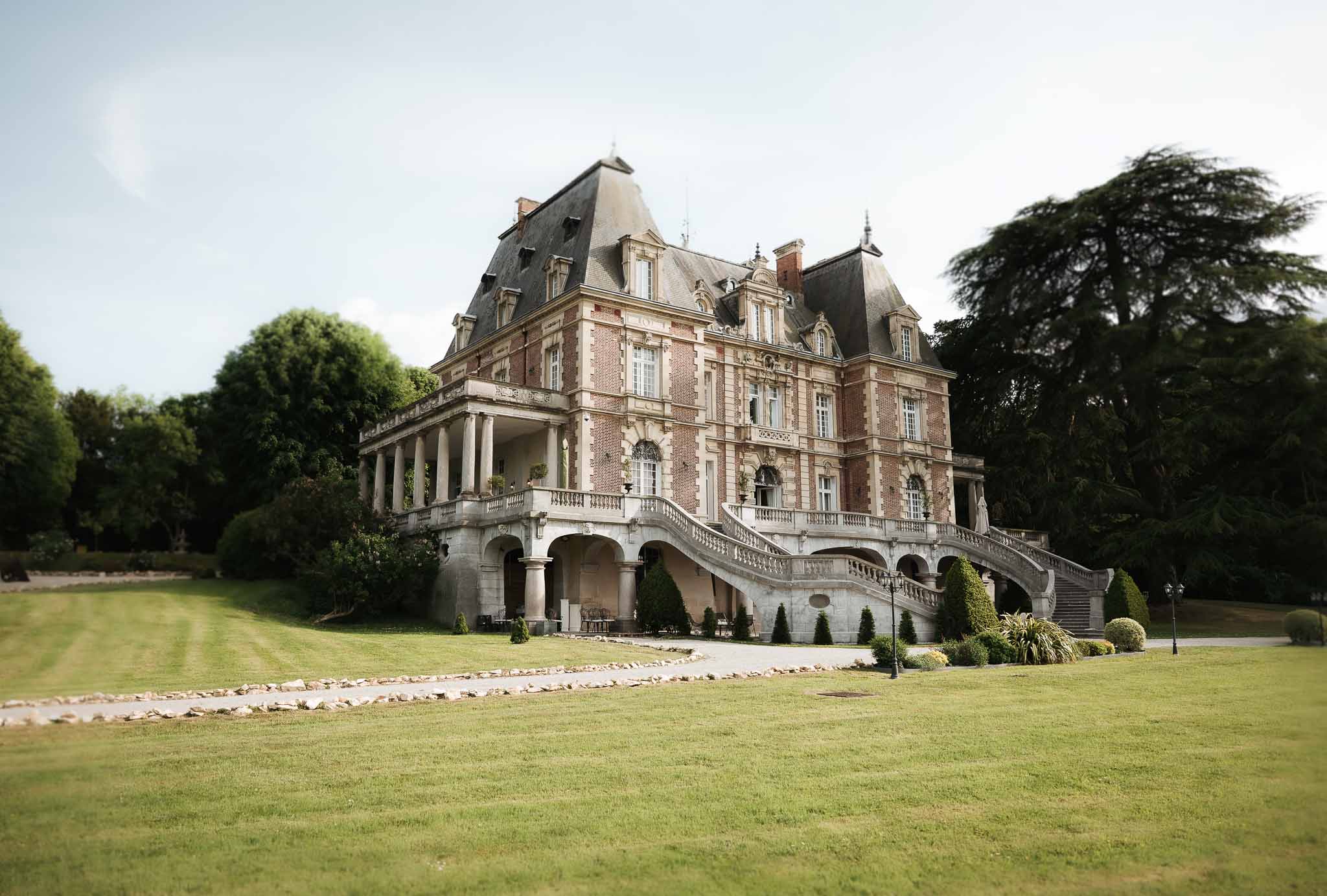 Second Empire chateau facade with red brick and limestone double-curved staircase and colonnaded terrace