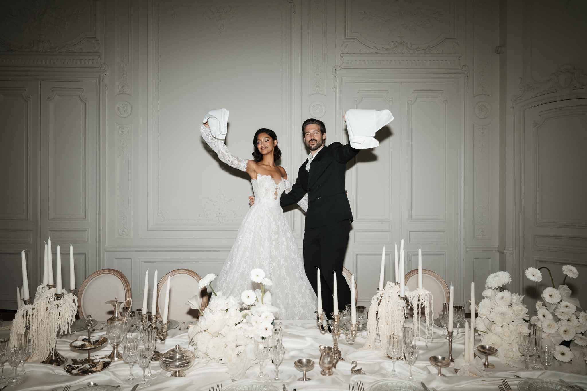 Bride and groom celebrating on dining table in elegant ballroom reception