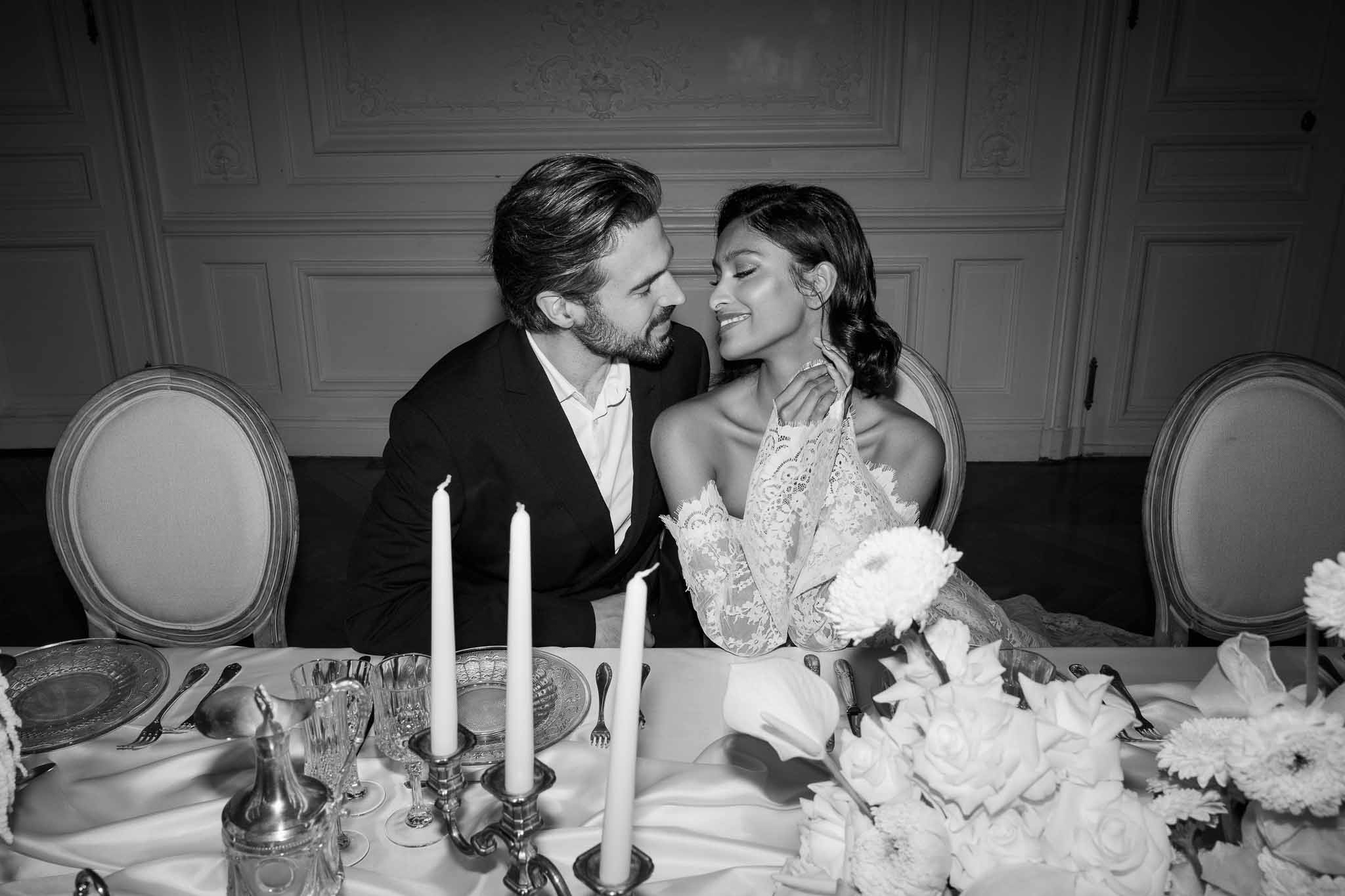 Bride and groom sharing intimate moment at reception table in elegant ballroom