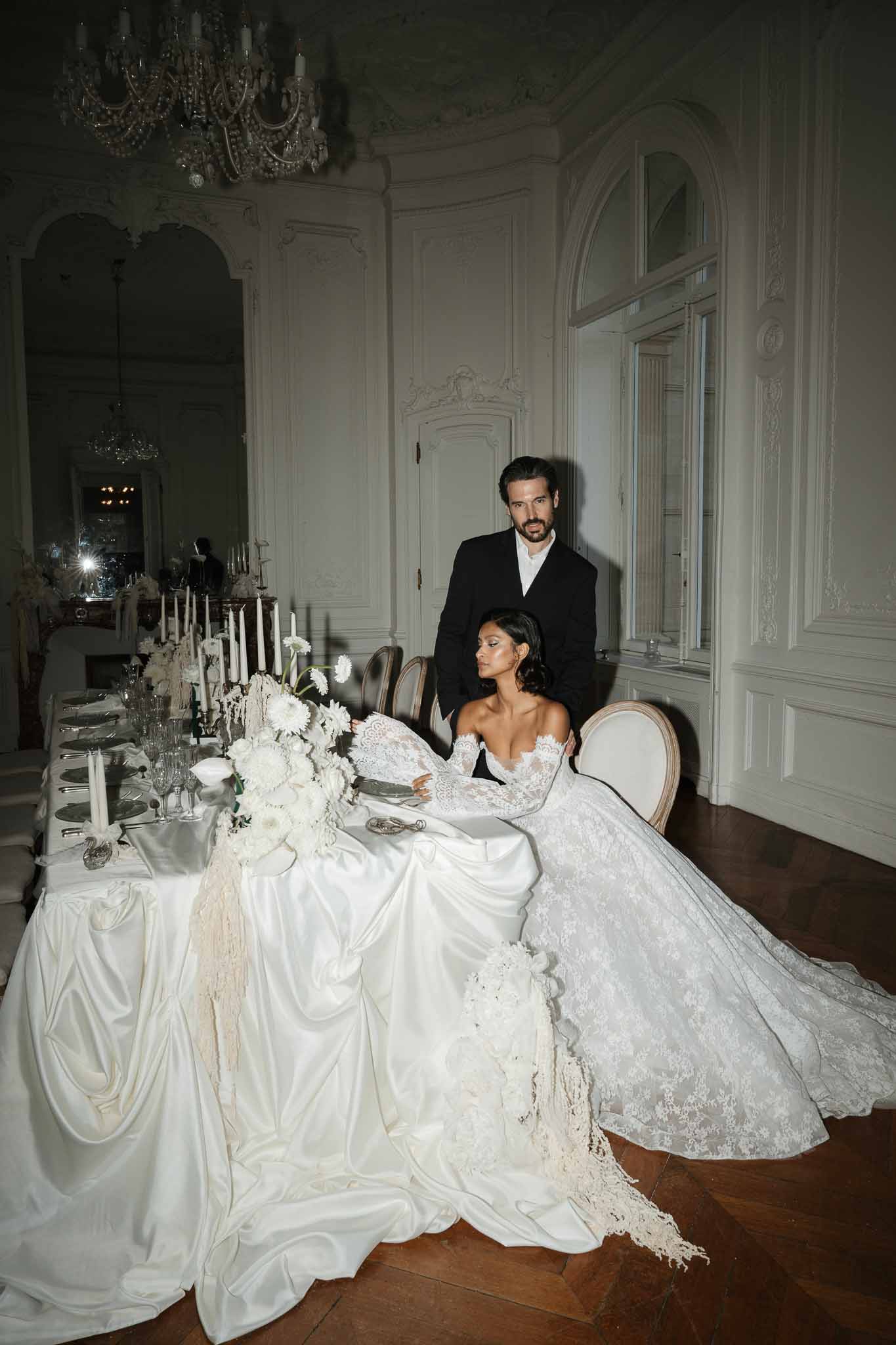 Bride and groom seated at formal dining table during reception in neoclassical ballroom