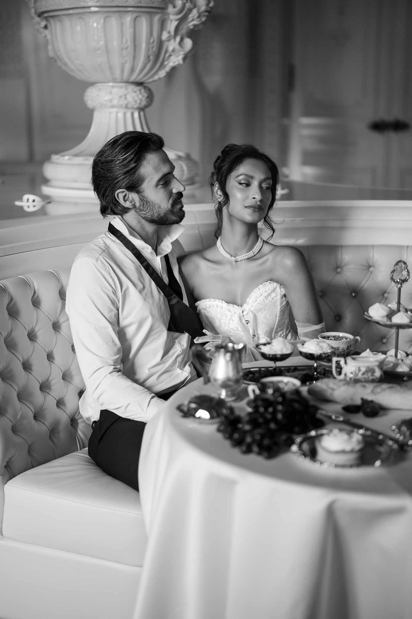 Bride and groom seated together at reception table in elegant indoor venue