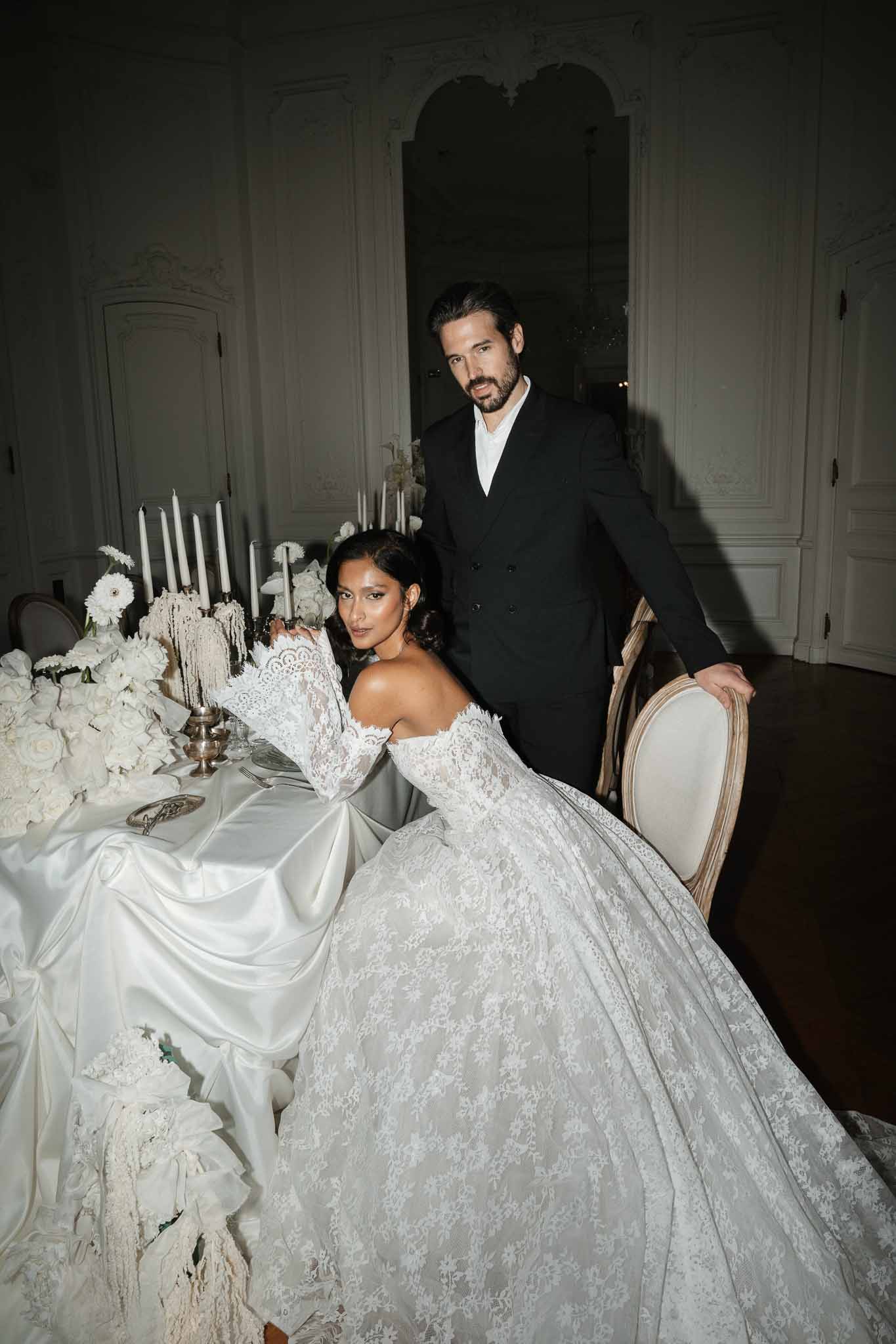 Bride and groom seated at elegantly set reception table in classical indoor venue