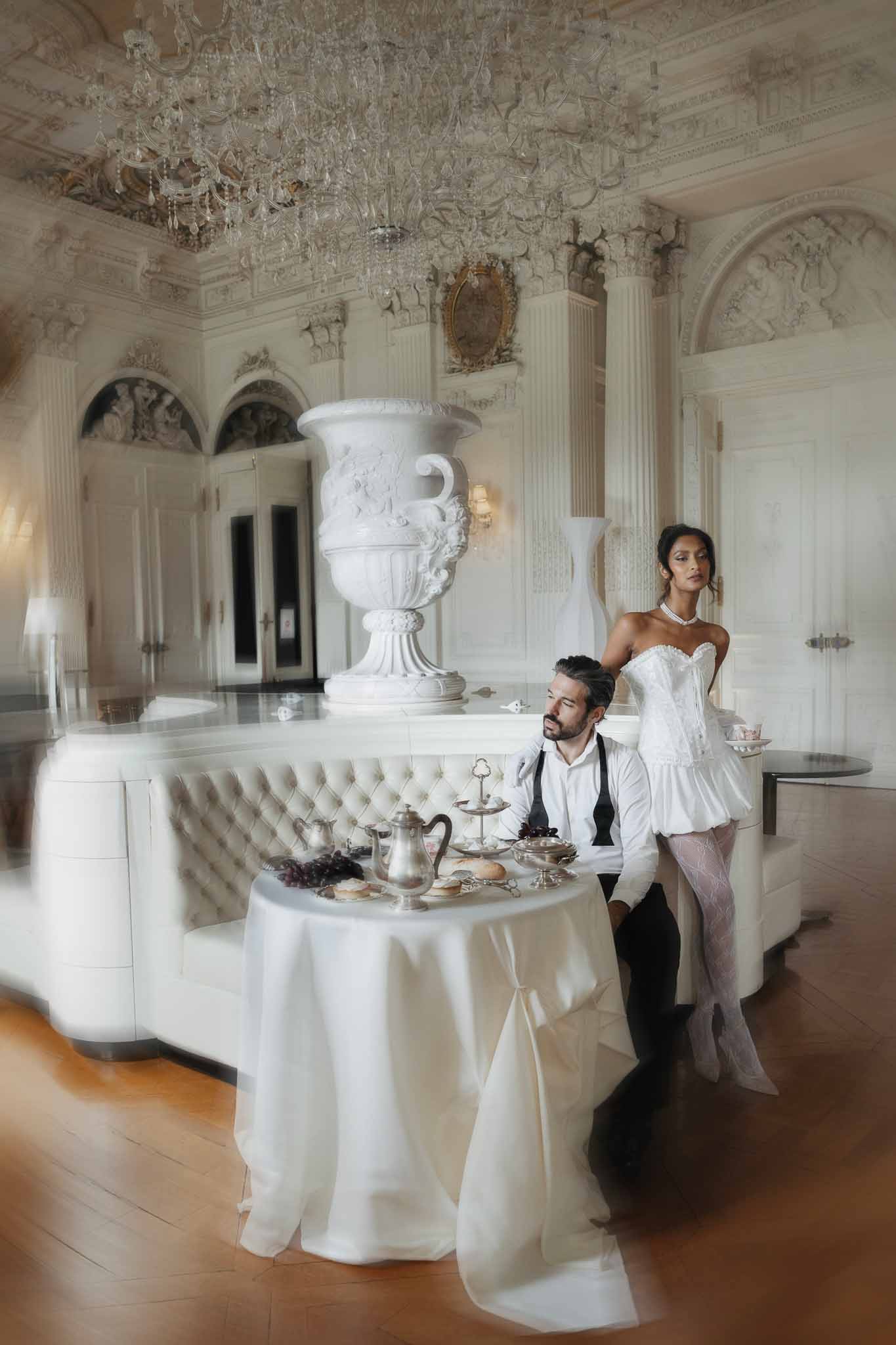 Bride and groom portrait in ornate neoclassical ballroom with crystal chandelier and classical columns