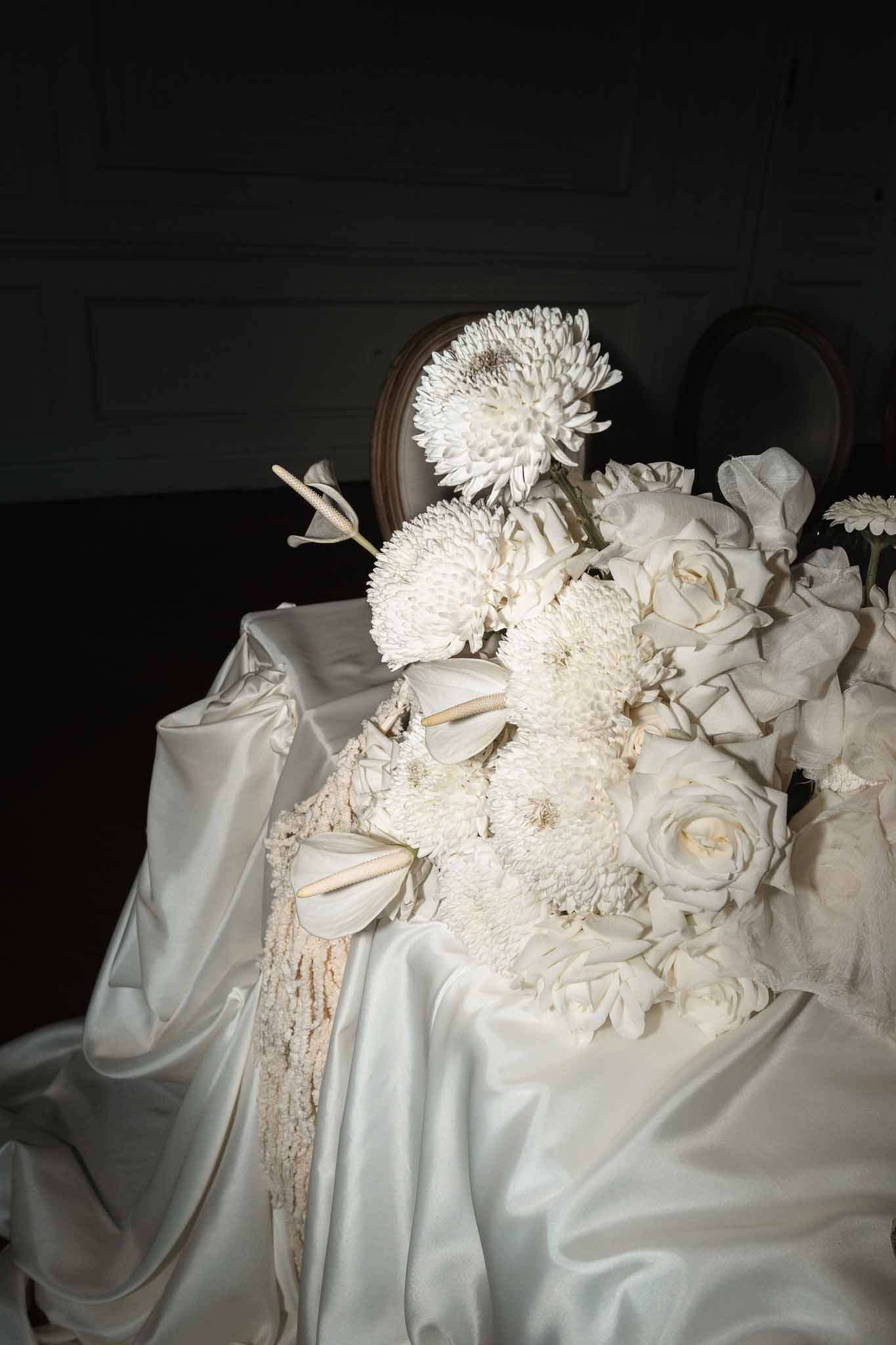 White dahlia and garden rose bridal bouquet with champagne ribbon on ivory silk fabric