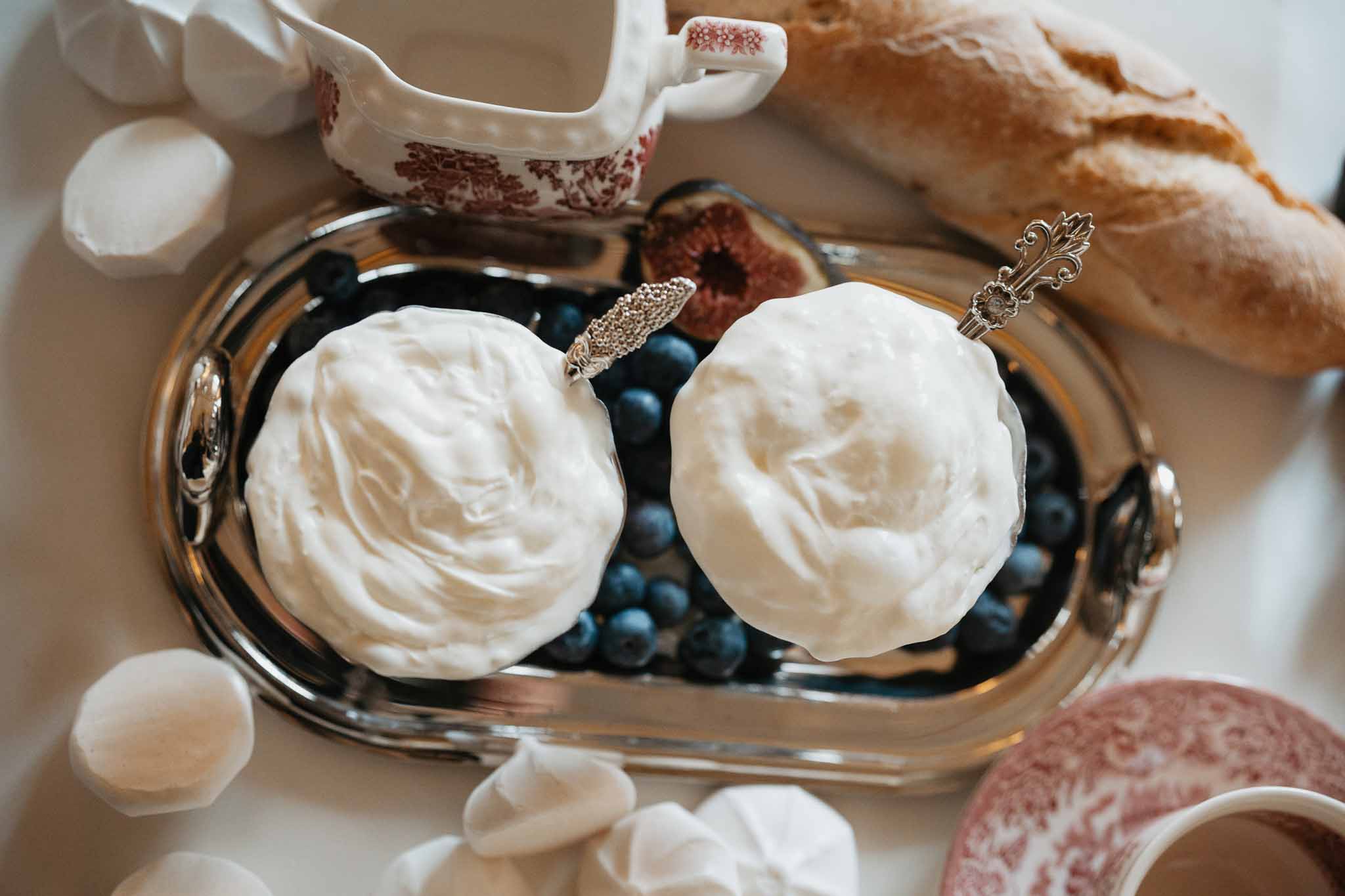 Elegant dessert table setting with cream meringues, blueberries, and vintage silver spoons at wedding reception