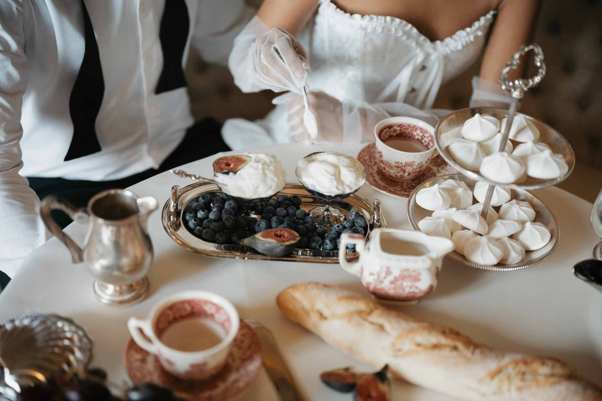 Elegant breakfast table setting with meringues and floral teacups at wedding brunch
