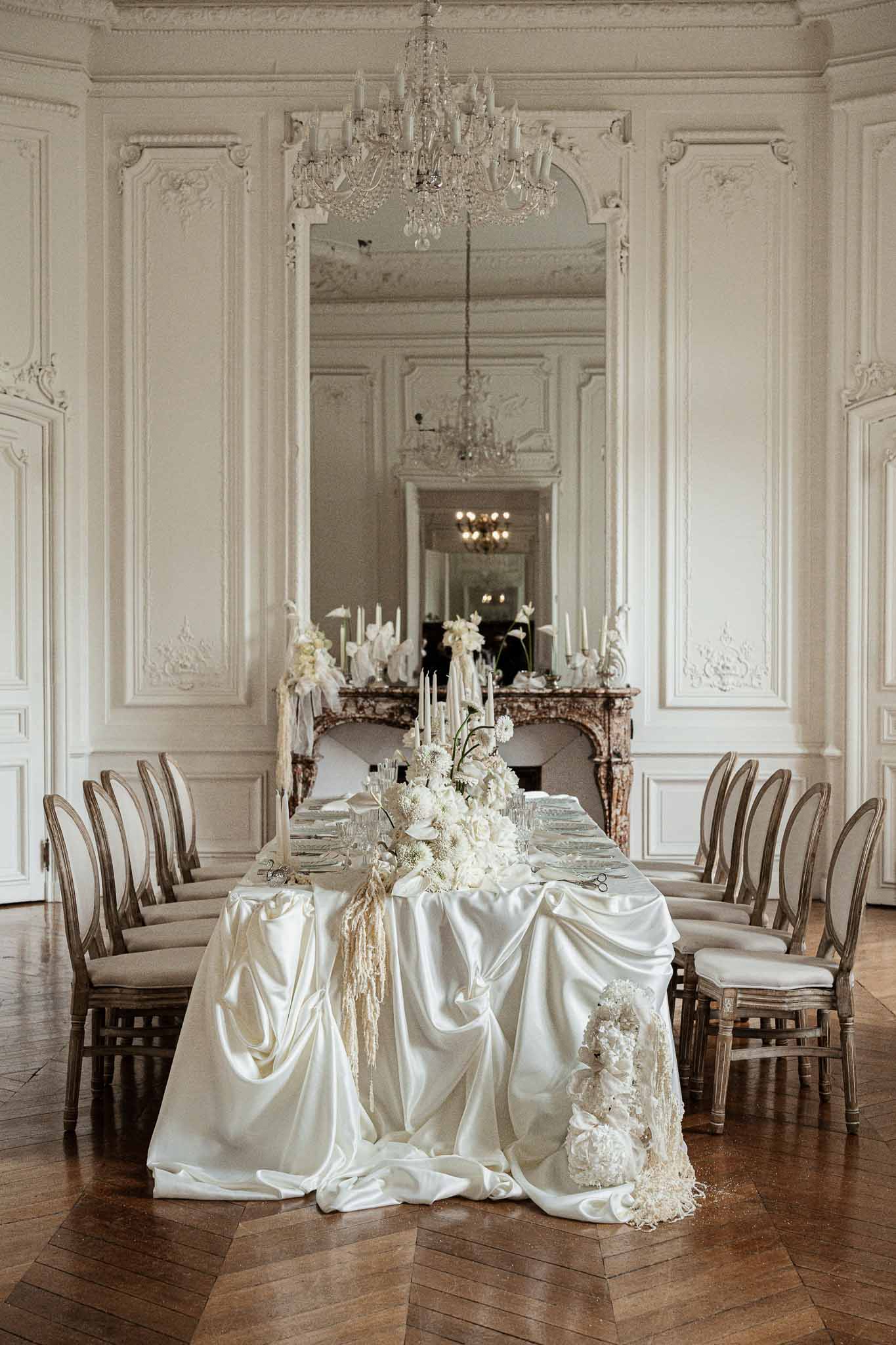 Elegant dining table setup in classical French ballroom with crystal chandelier and ornate architecture