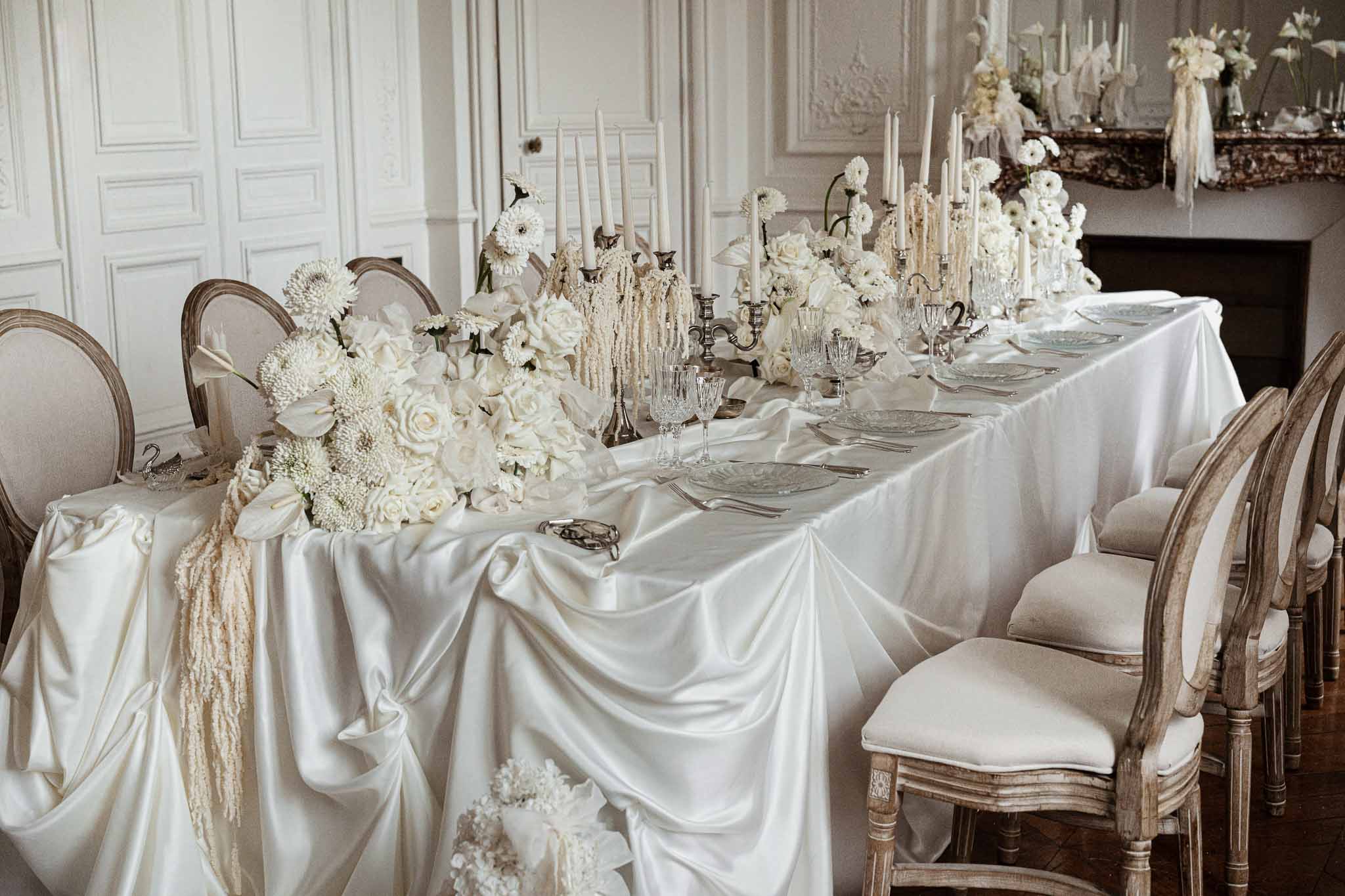 Elegant reception table with white florals and ivory linens in classical ballroom setting