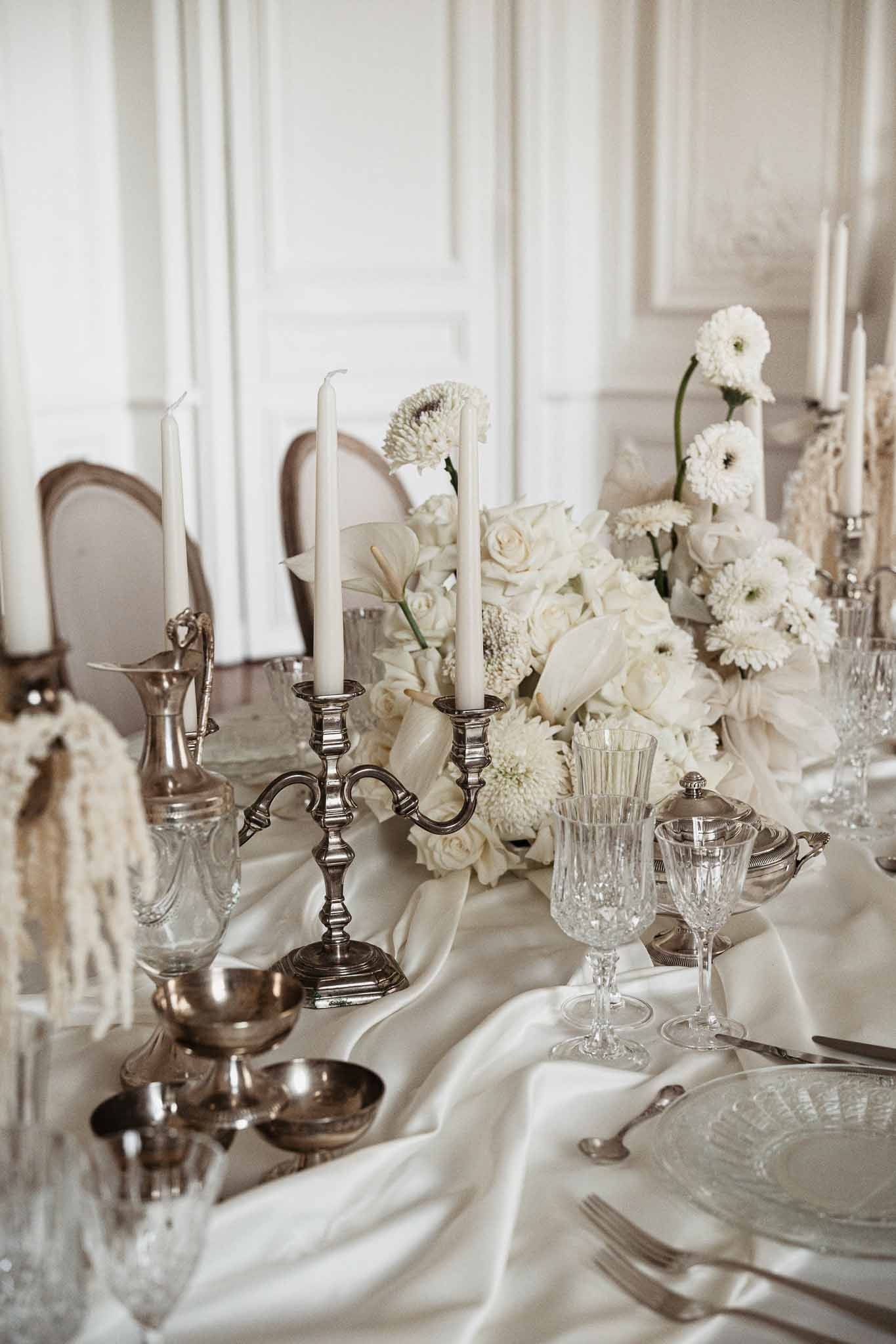 Elegant white floral centerpieces and silver candelabras on formal reception table at indoor wedding venue