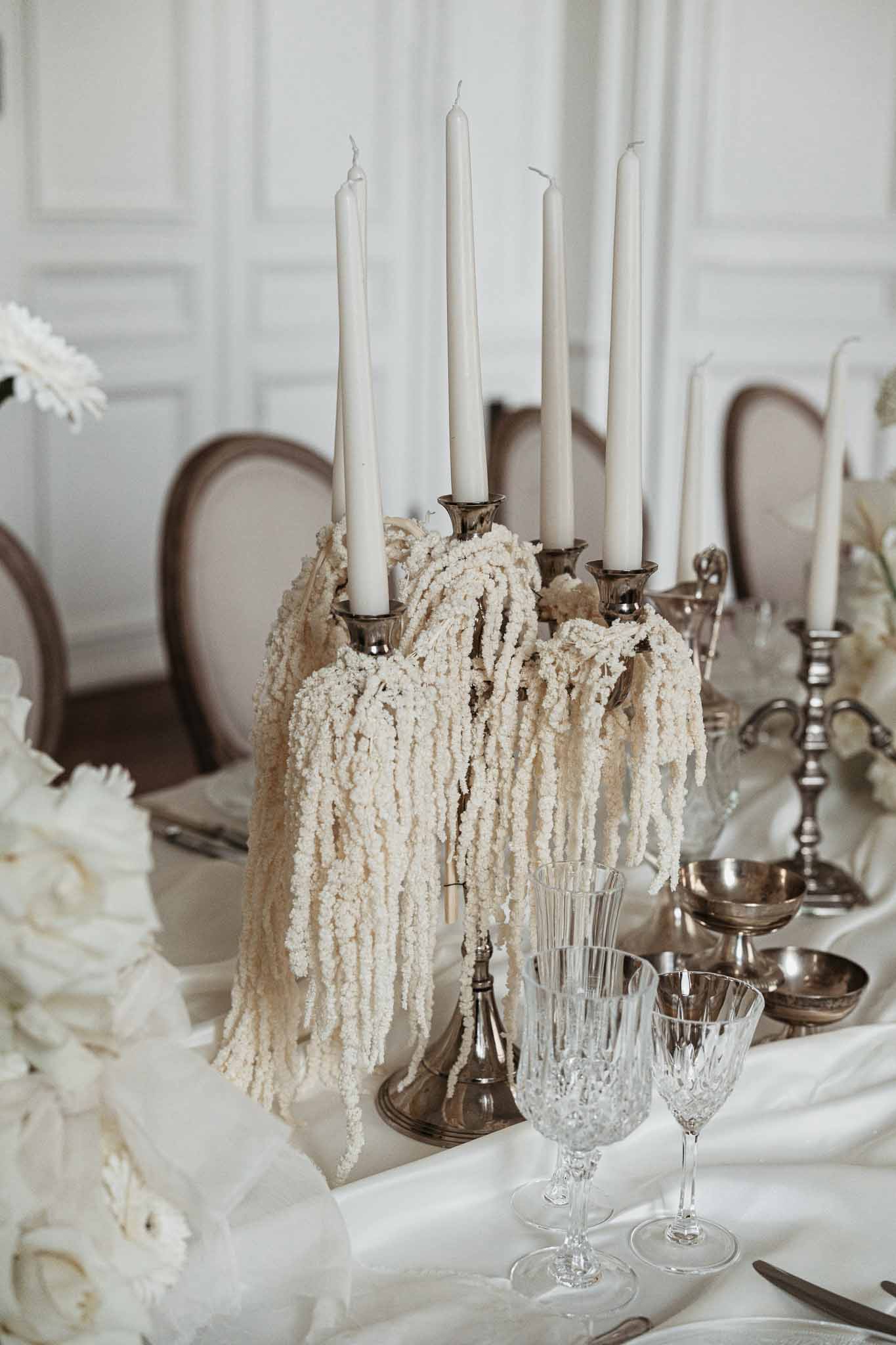 Silver candelabra centerpiece with cream candles and beaded garland at formal reception table