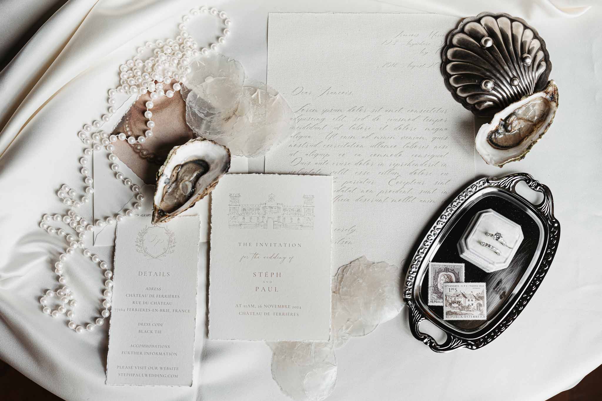 Wedding stationery flat lay with rings, pearls, and oyster shells at Château de Ferrières