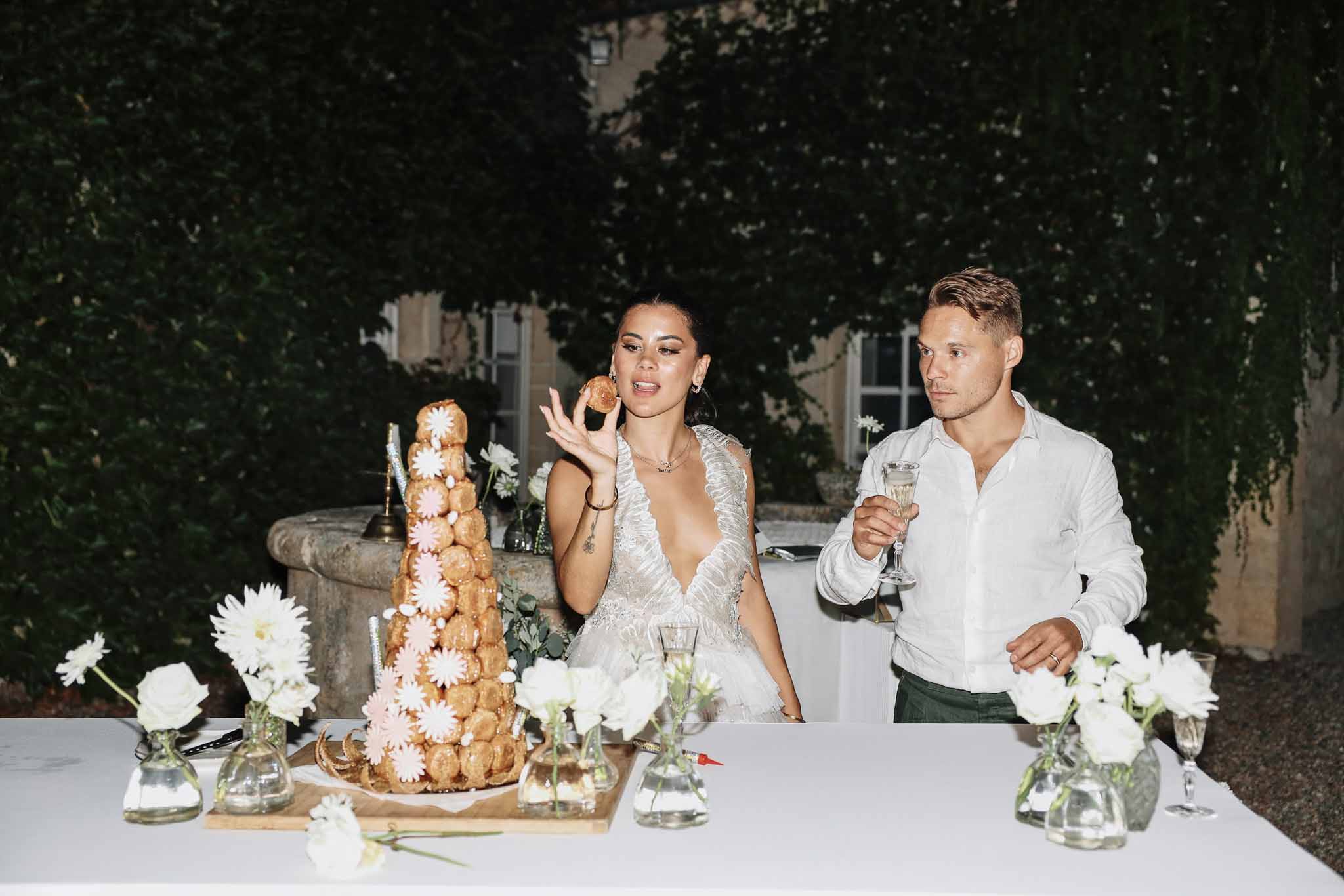 Bride and groom cutting croquembouche at sweetheart table during outdoor evening chateau reception