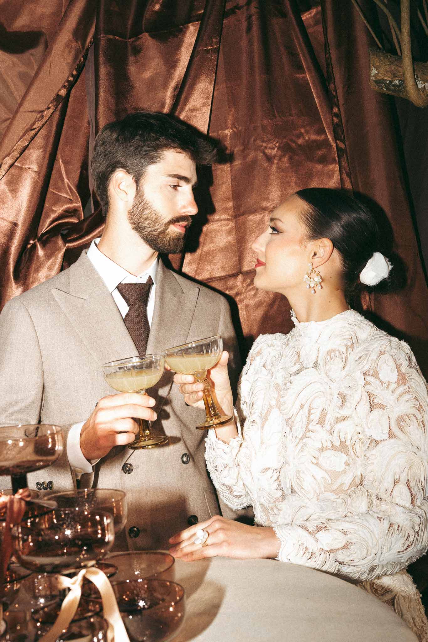 Bride and groom sharing champagne toast during wedding reception with velvet backdrop