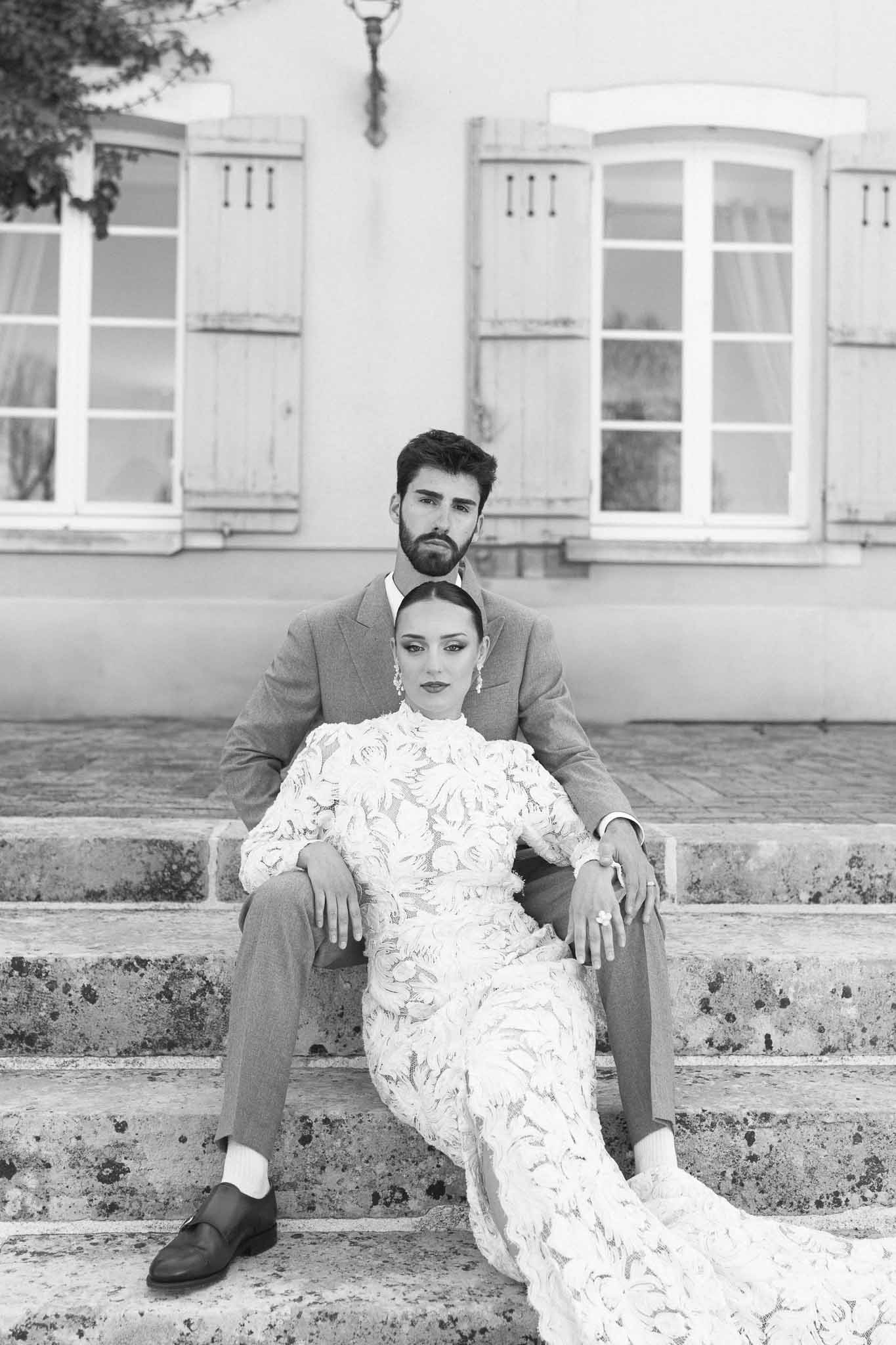 Bride and groom seated together in front of classical white building facade