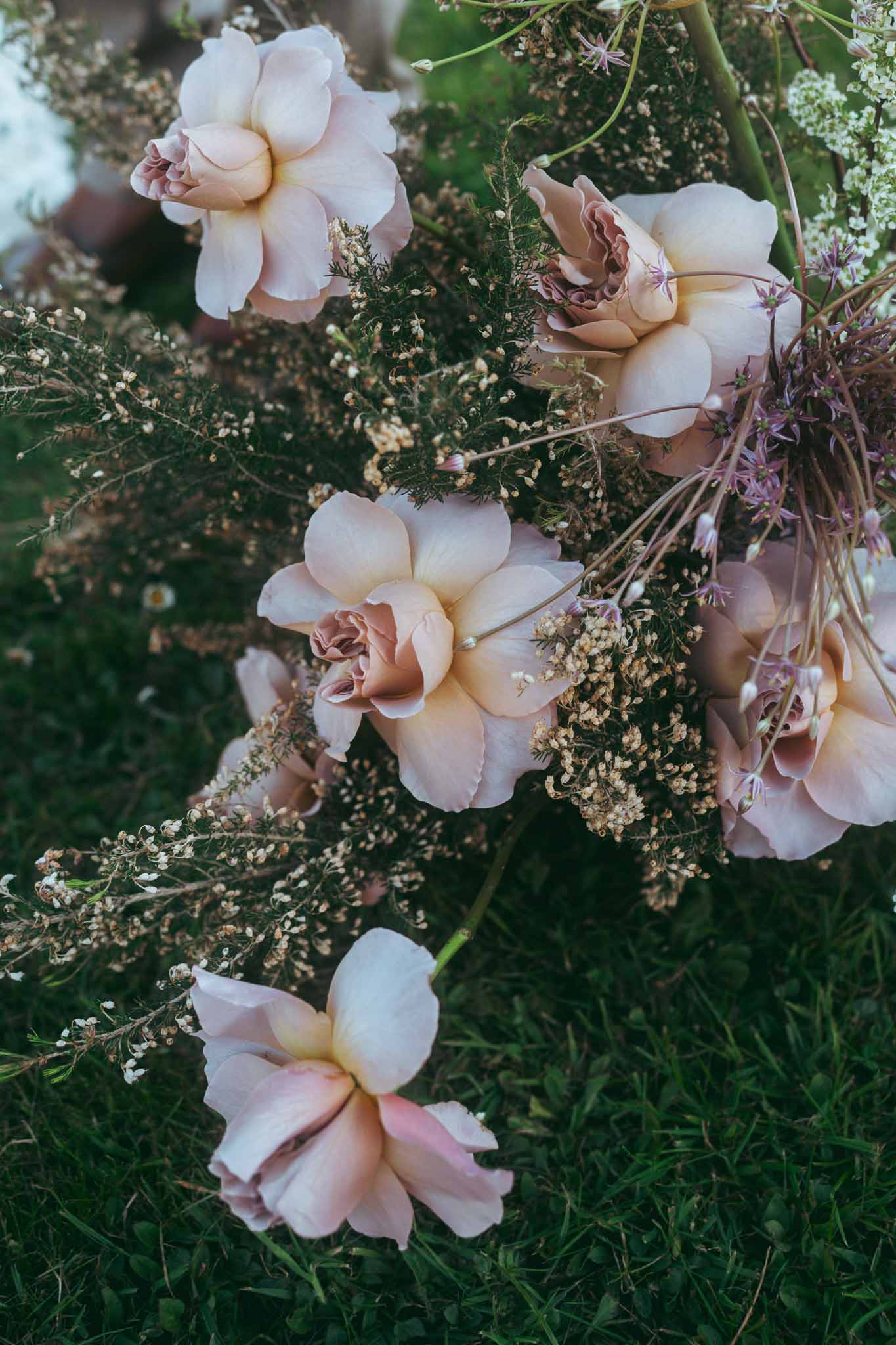 Close-up of bridal bouquet with blush roses and dried botanicals in romantic garden style