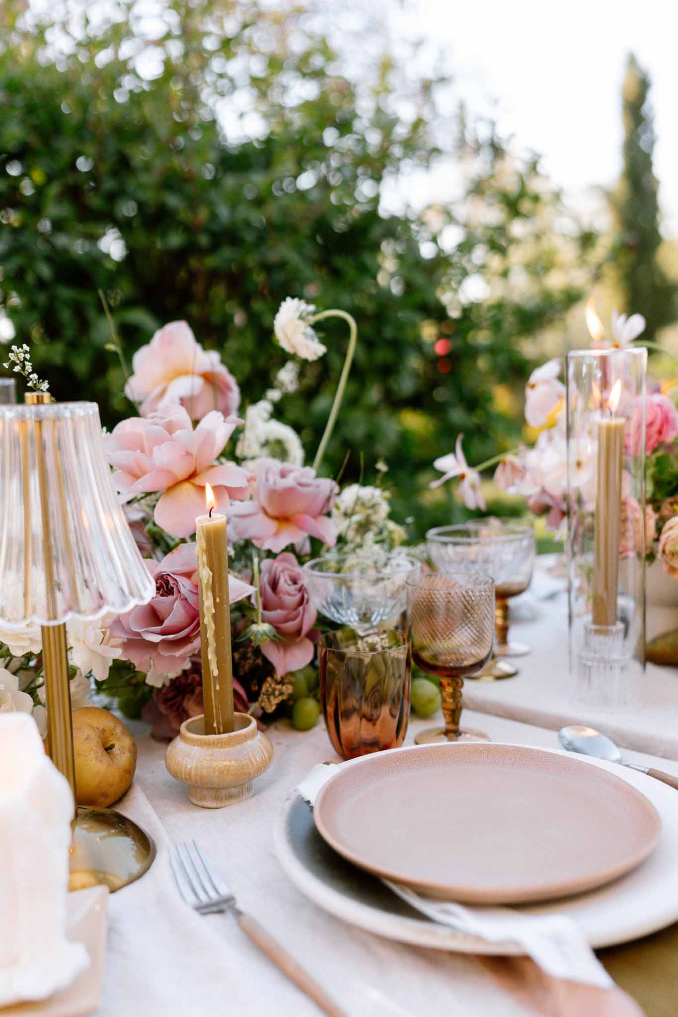 Reception table setting with blush plates and floral centerpieces in garden venue