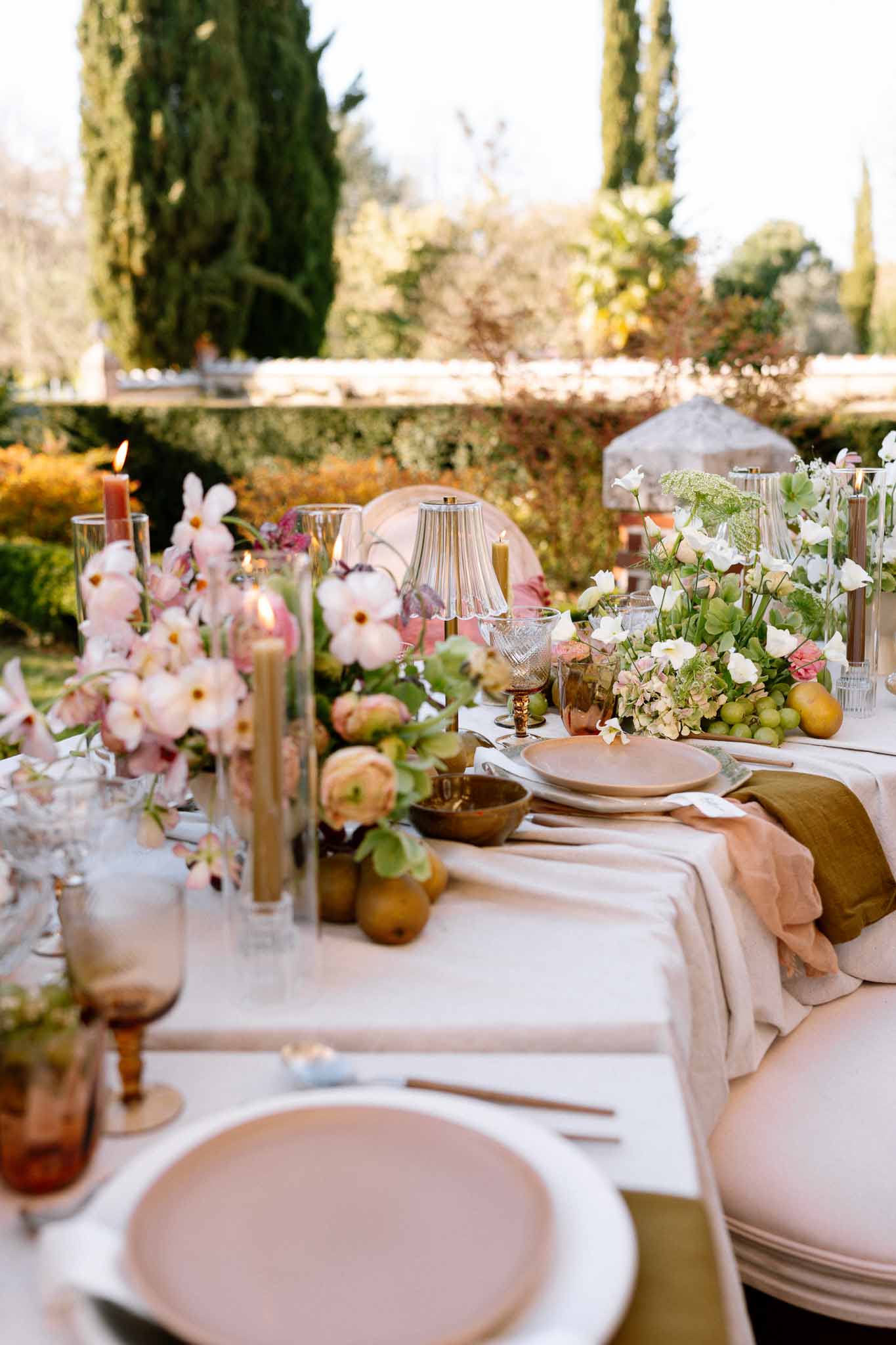 Garden reception table with ivory linens, dusty rose napkins, and pink peony centerpieces at outdoor venue
