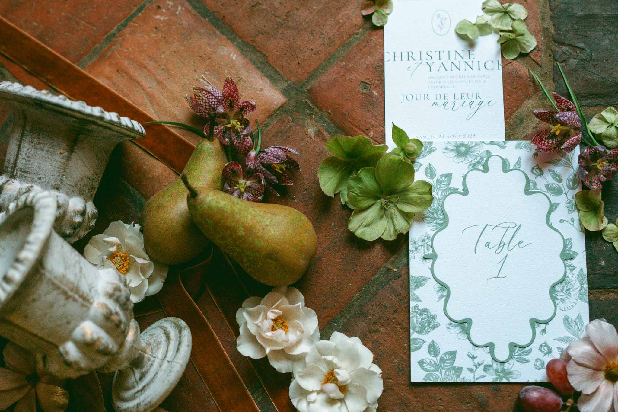 Wedding invitation flat lay with autumn florals and stationery on terra cotta tiles