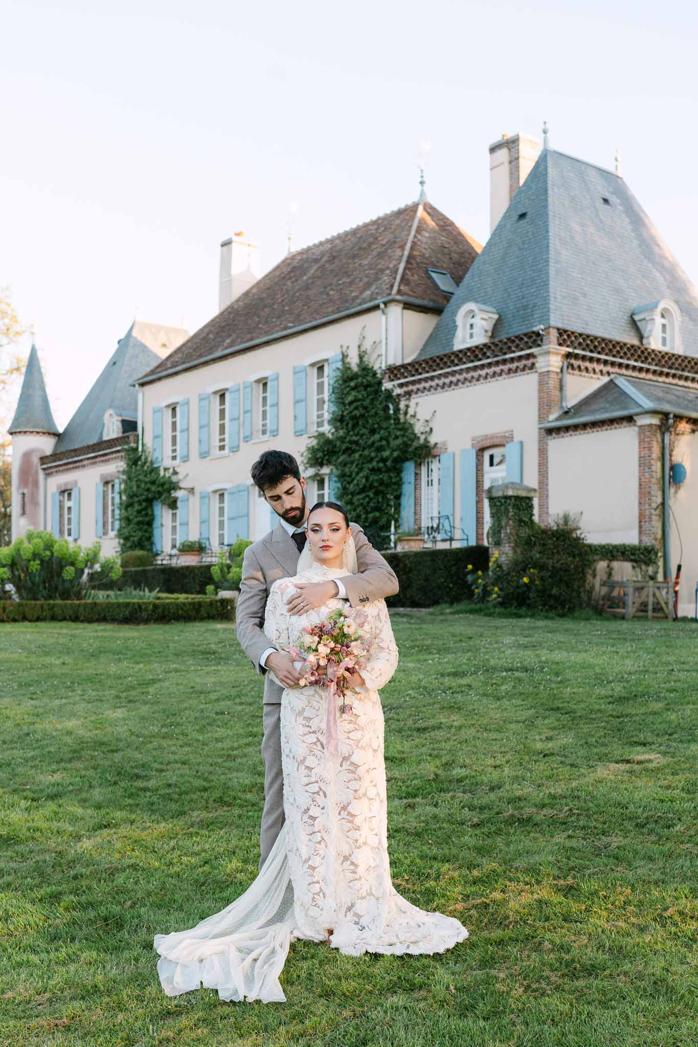 Bride and groom portrait on château lawn during golden hour wedding photography