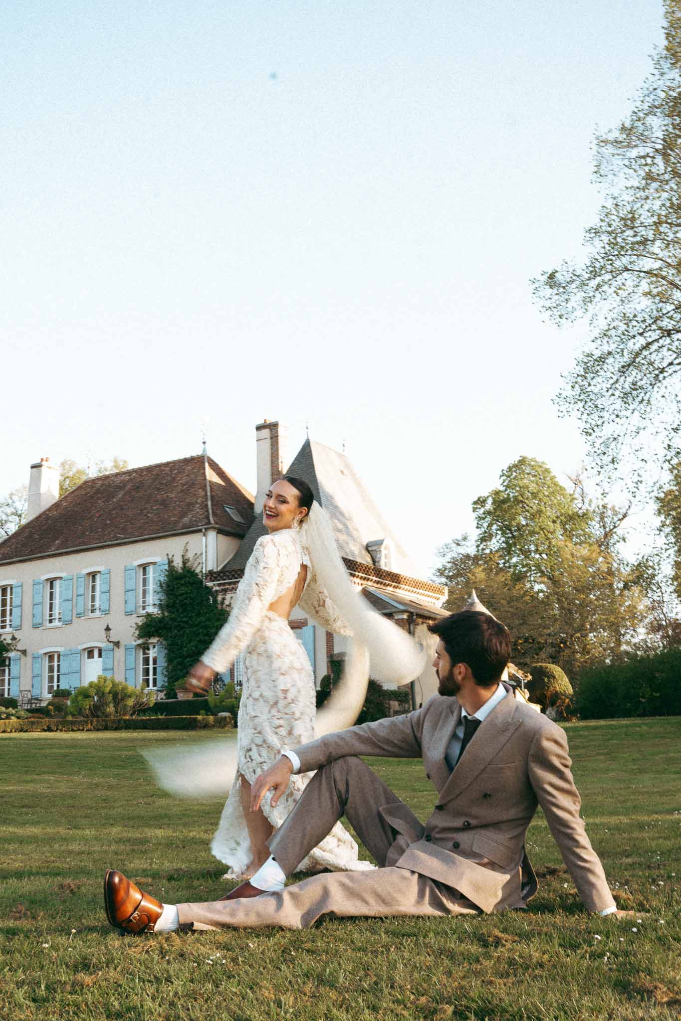 Bride and groom playful portrait moment on manor house lawn with French estate in background