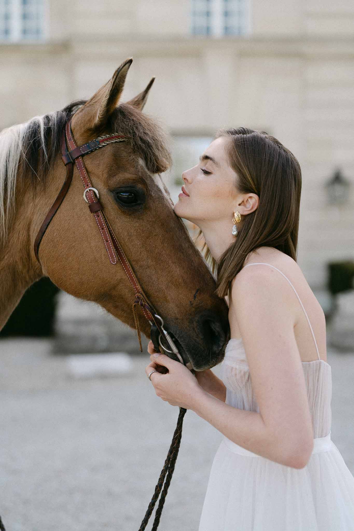 Bride with bay horse in urban courtyard wedding portrait