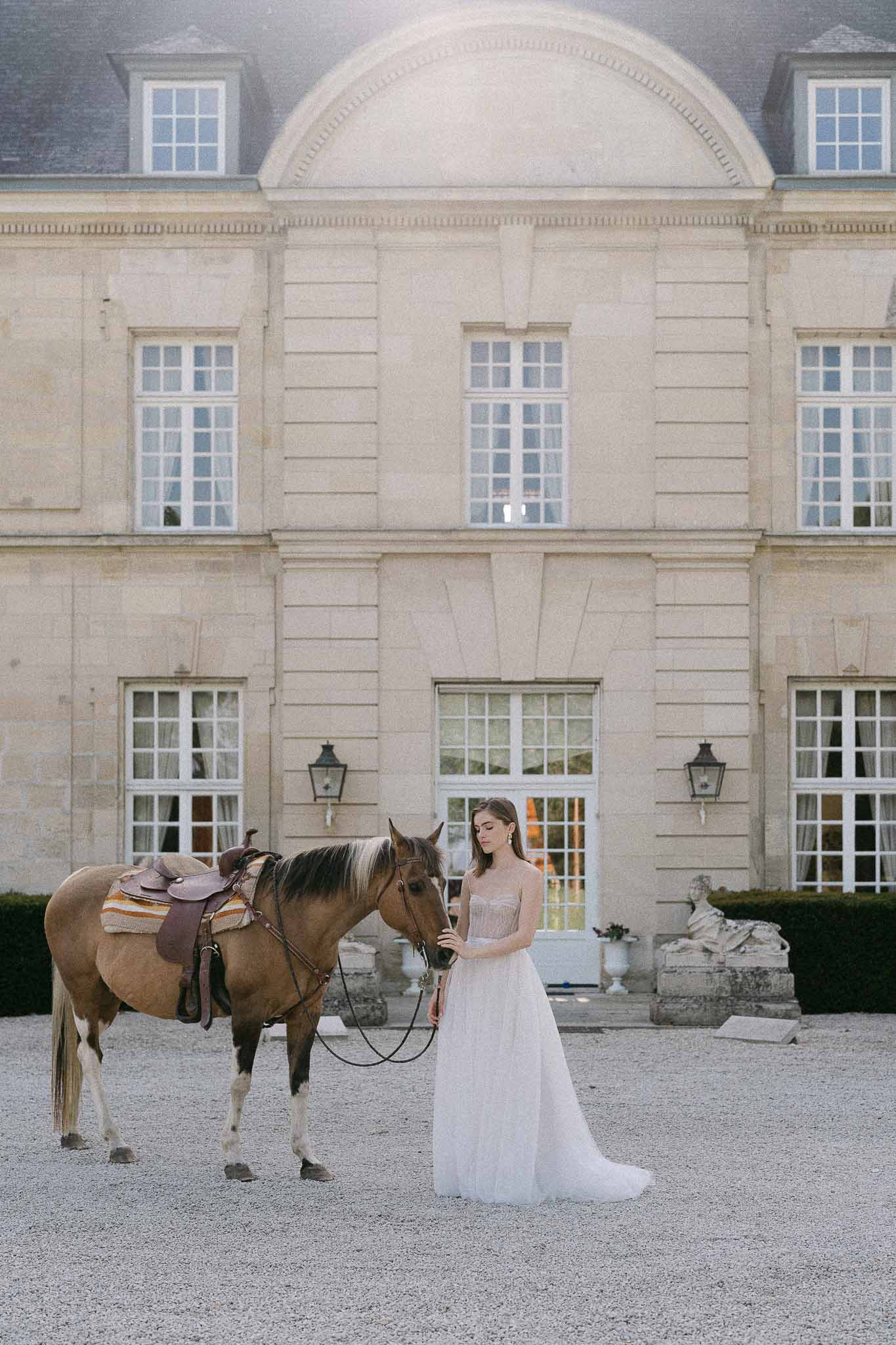 Bride with horse in front of neoclassical stone mansion wedding venue