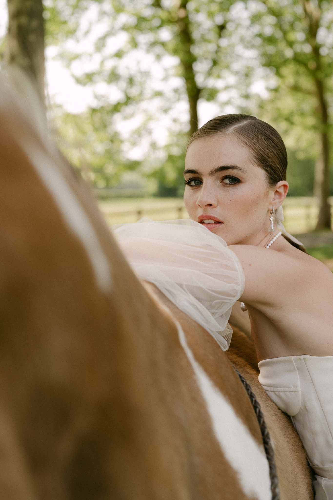 Bride in ivory wedding dress and pearl jewelry portrait in garden setting